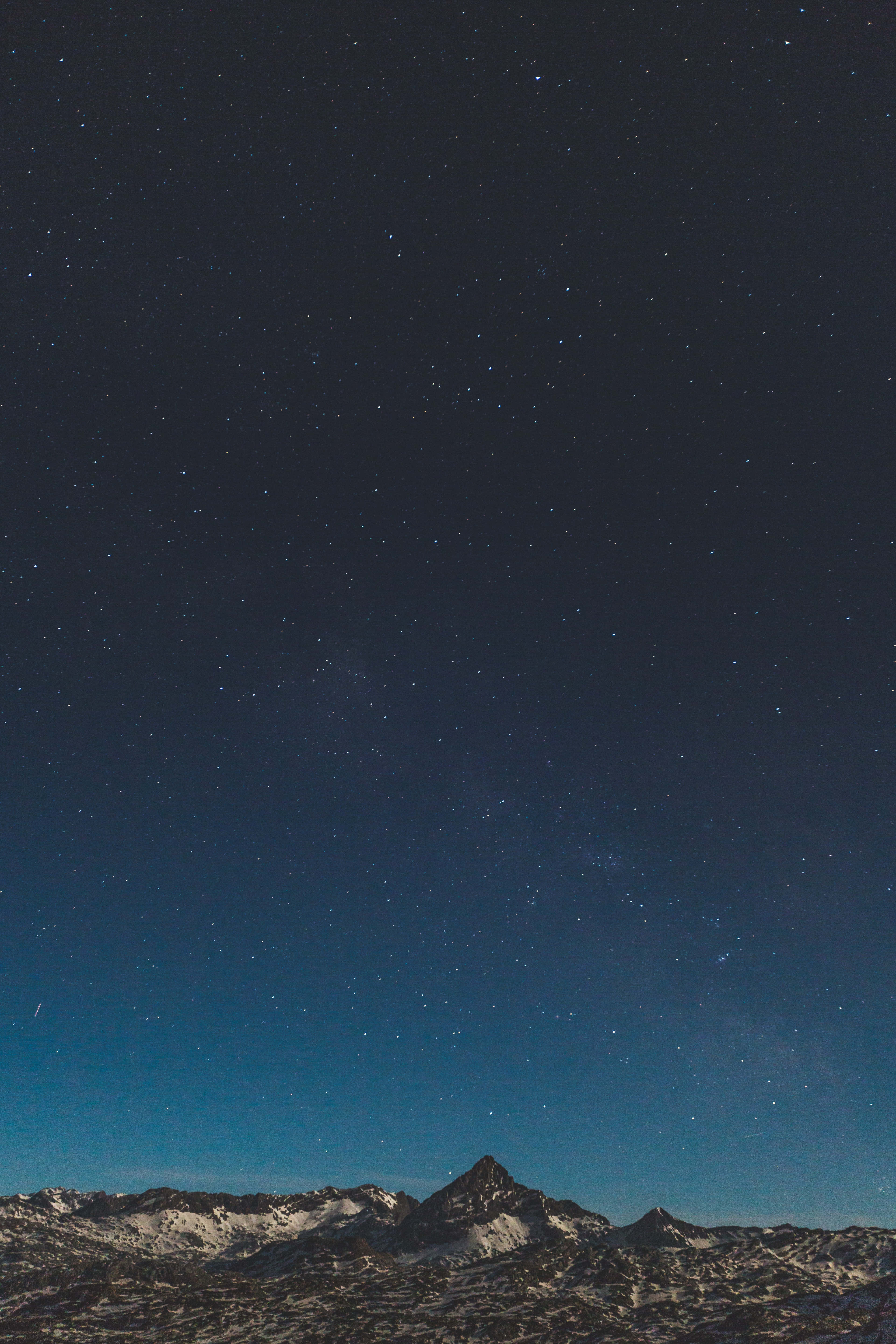 簡約風格 桌布 壁紙 — 積雪的山峰在廣闊的星空夜空下聳立，散發著宇宙藍和深靛藍色調。