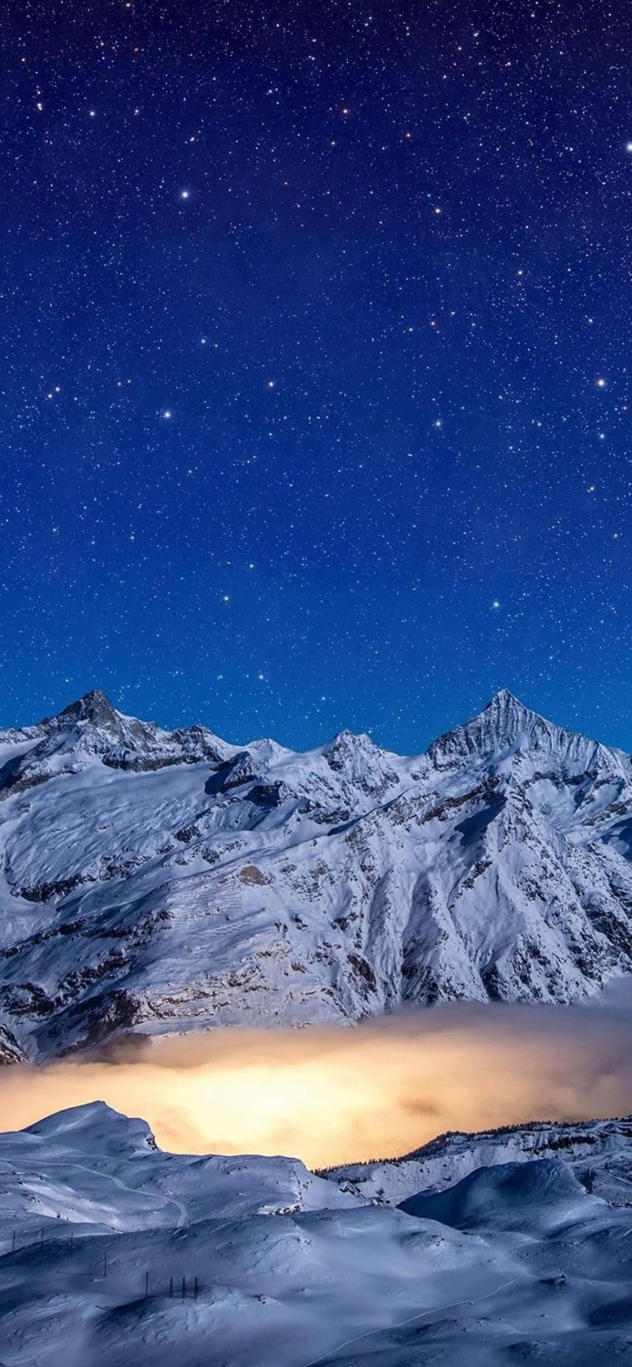 Mountain iPhone 桌布 壁紙 — 積雪的山峰在星空下升起，下方有一層發光的雲層。