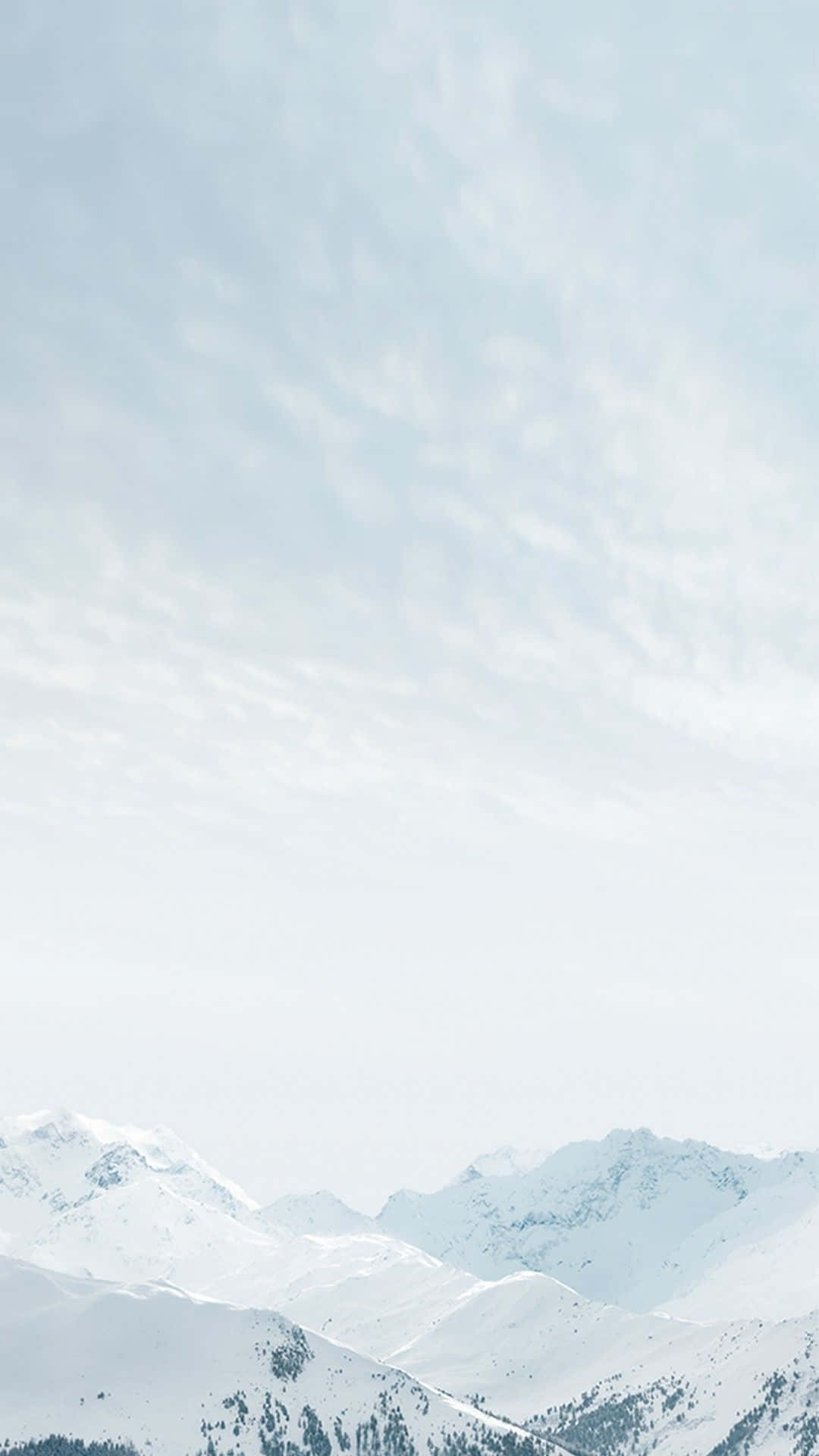 可愛 iPhone 壁紙 桌布 壁紙 — 積雪的山峰在柔和淡藍色的天空下升起，伴隨著縷縷薄雲。