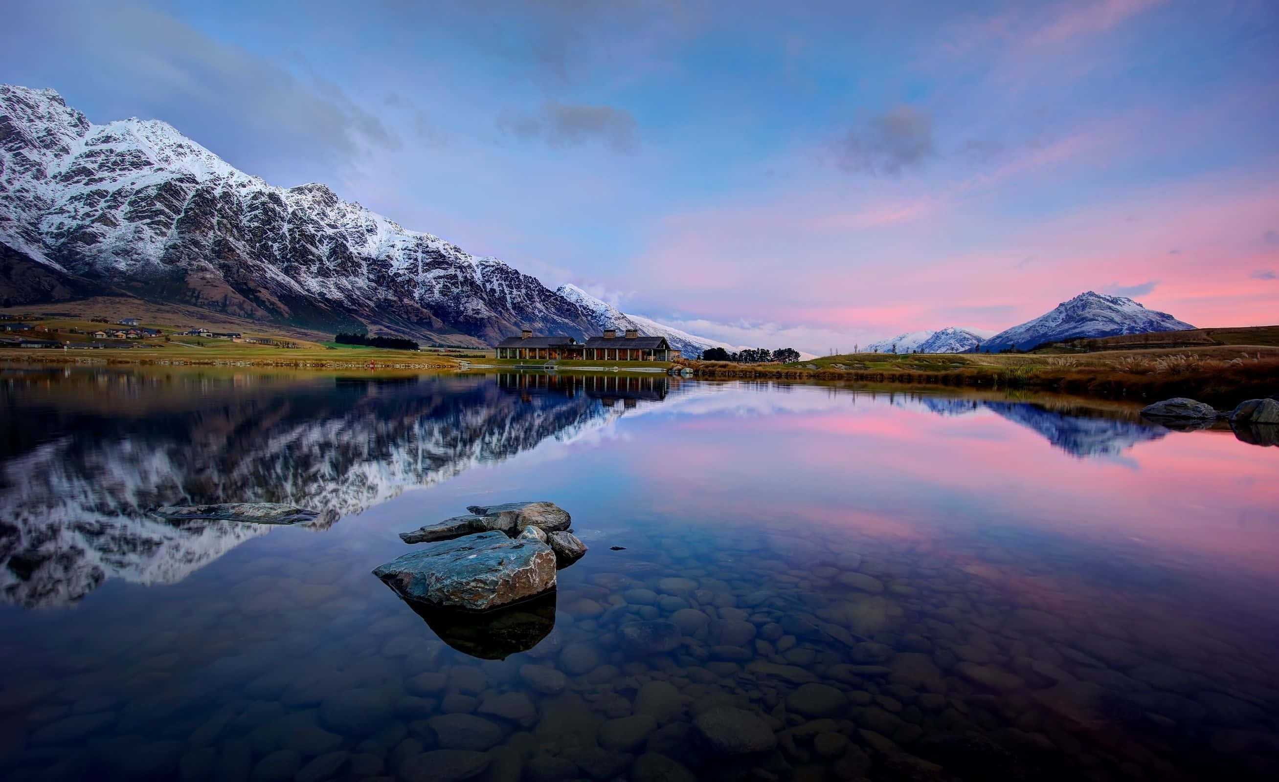 New Zealand 桌布 壁紙 — 積雪的山峰在黃昏時分倒映在玻璃般的湖面上，天空呈現粉紅色和藍色。