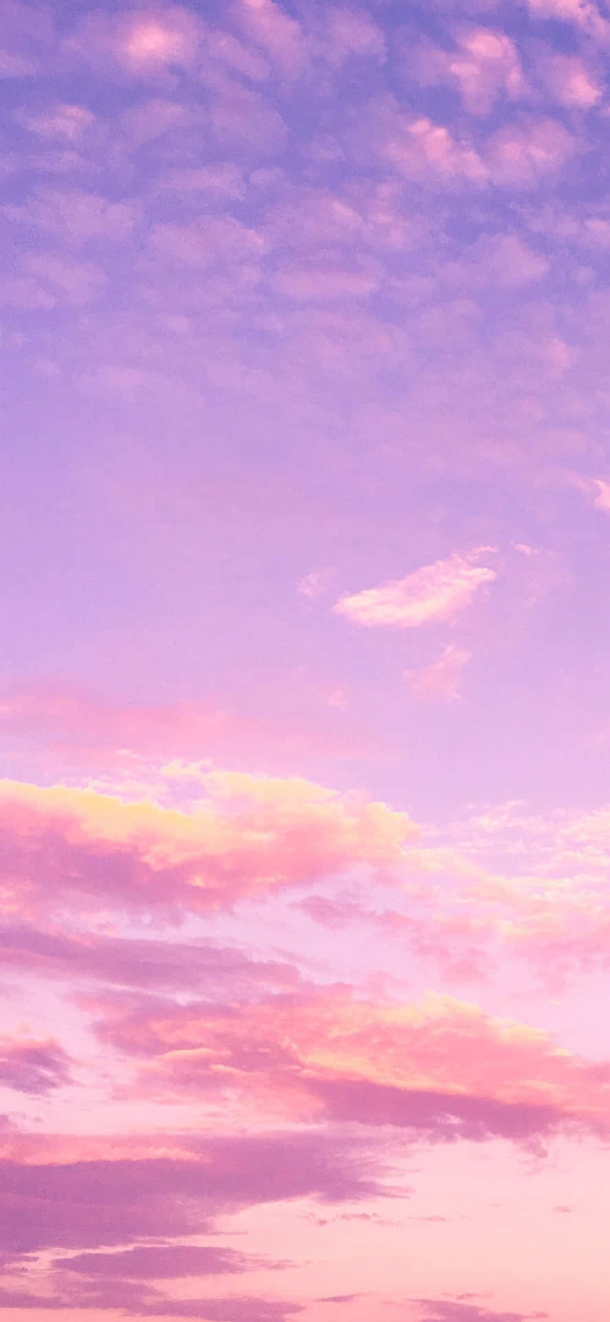 寧靜的天空中柔和的粉紅、紫色和黃色日落雲彩。