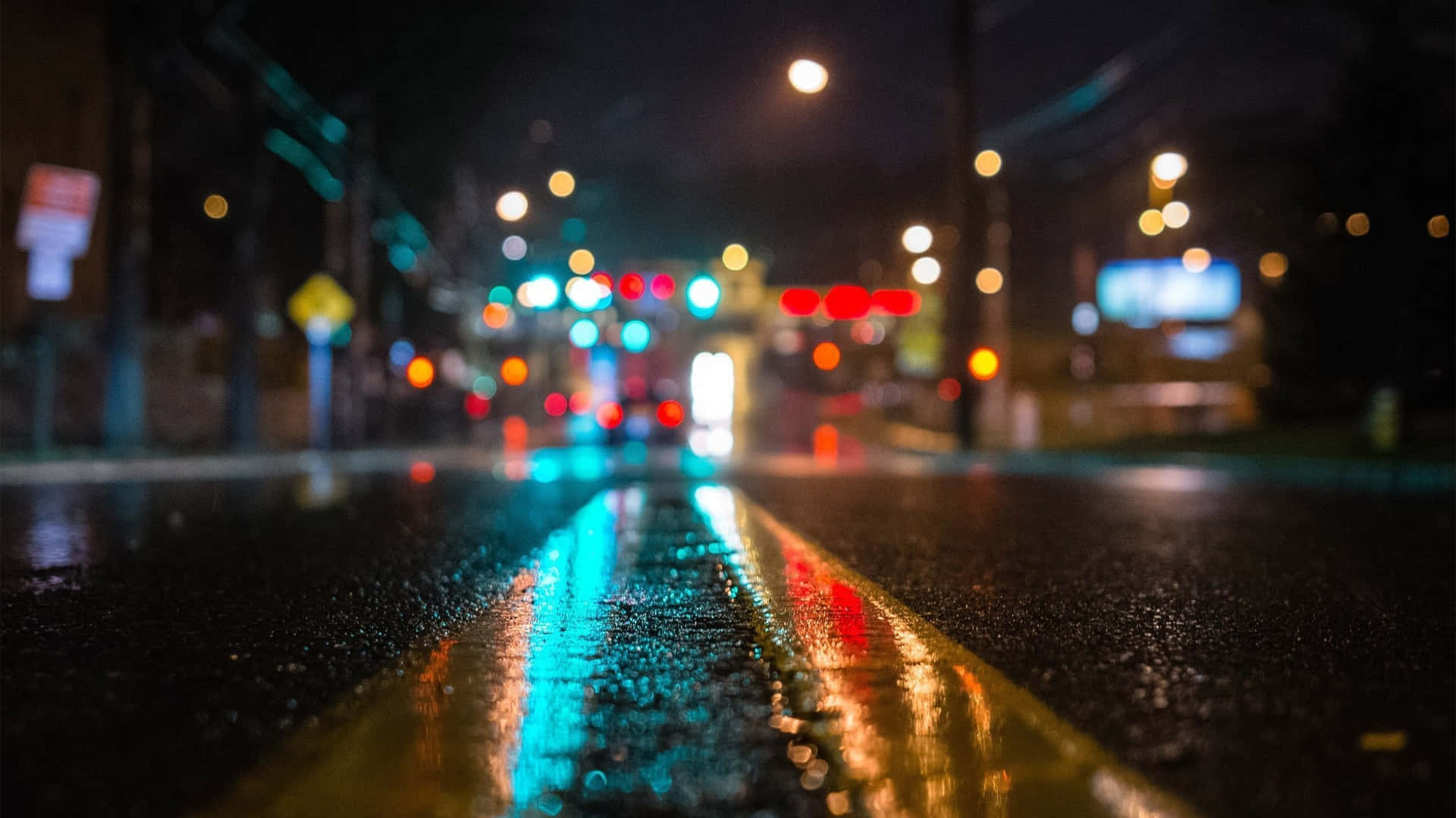 雨夜街道，發光的交通燈反射在濕路面上。
