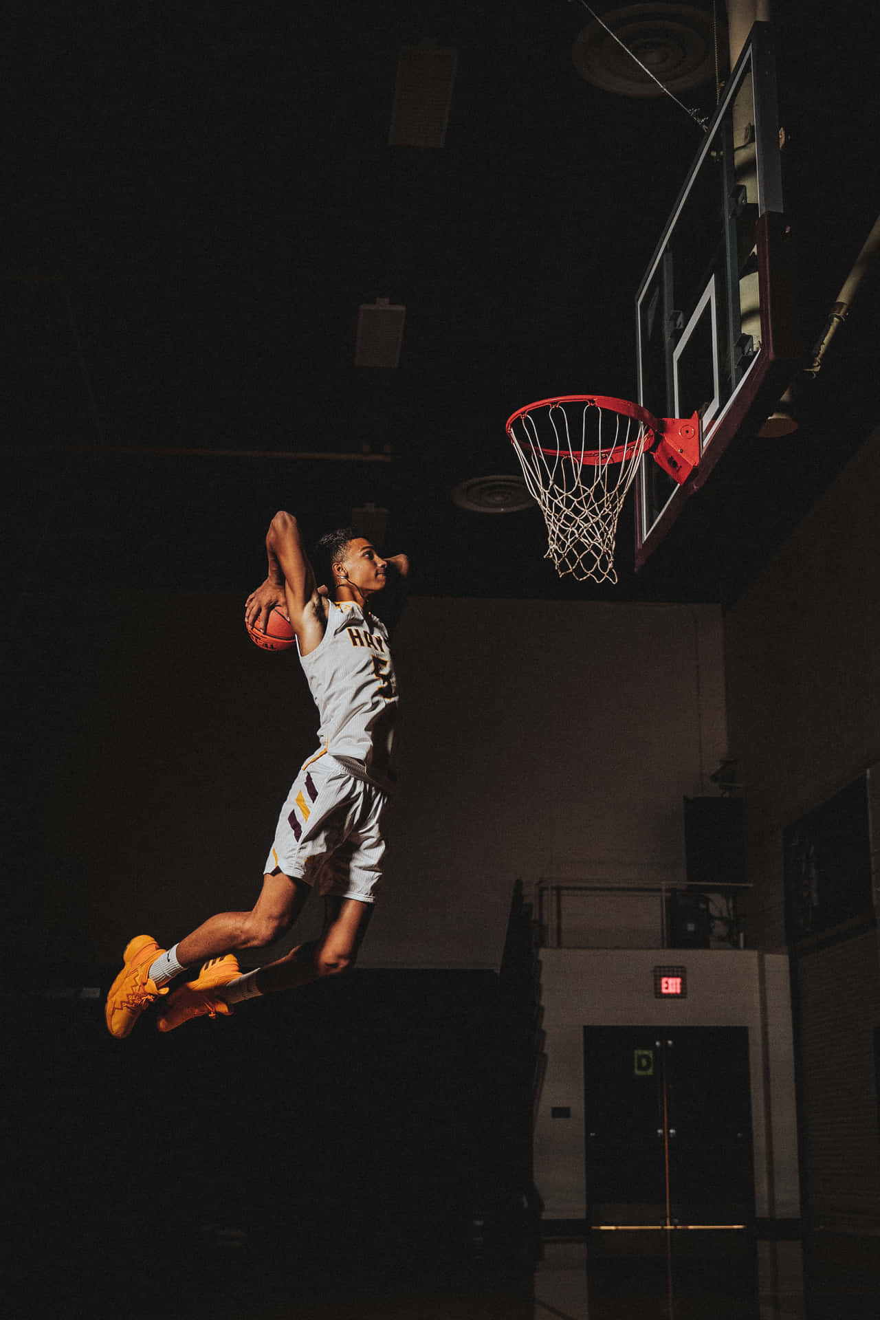 運動員在光線昏暗的室內籃球場上完成一次強力入樽。