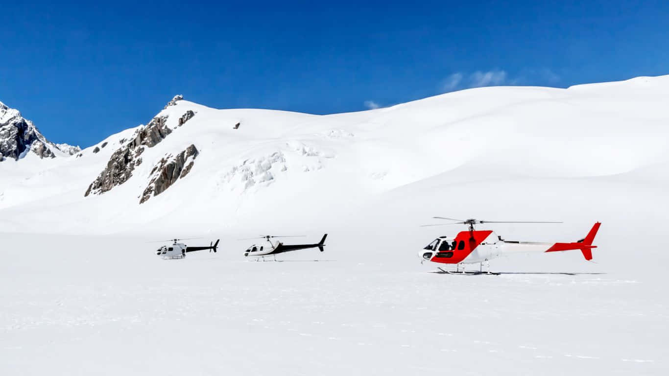空中群機編隊飛行壯觀景象 壁紙 — 三架直升機在廣闊的雪山平原上休息，天空清澈湛藍，遠處有岩石山峰。