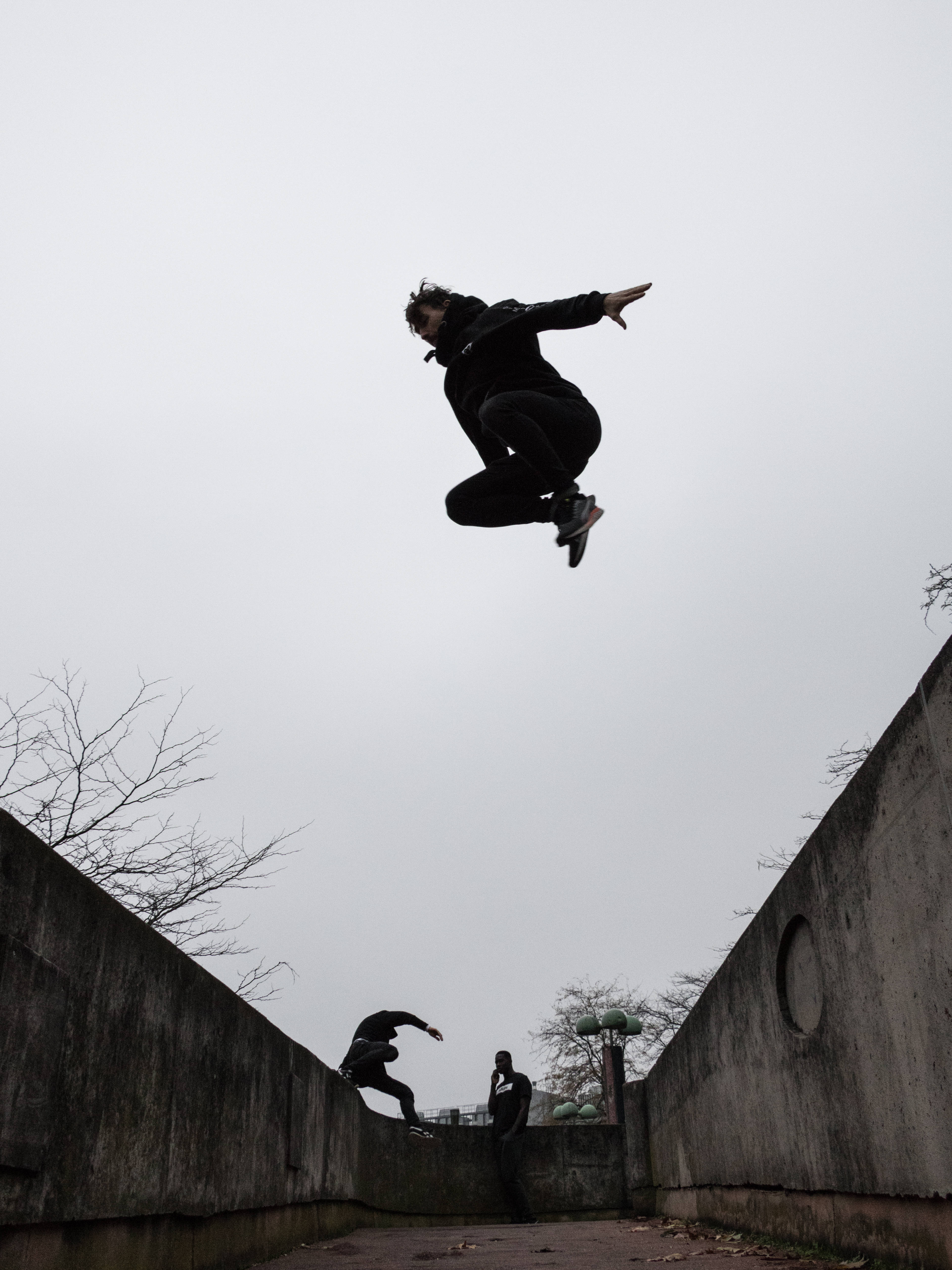 空中跑酷男子 壁紙 — 一名滑板手在半空中，在陰天下的混凝土坡道上表演技巧。