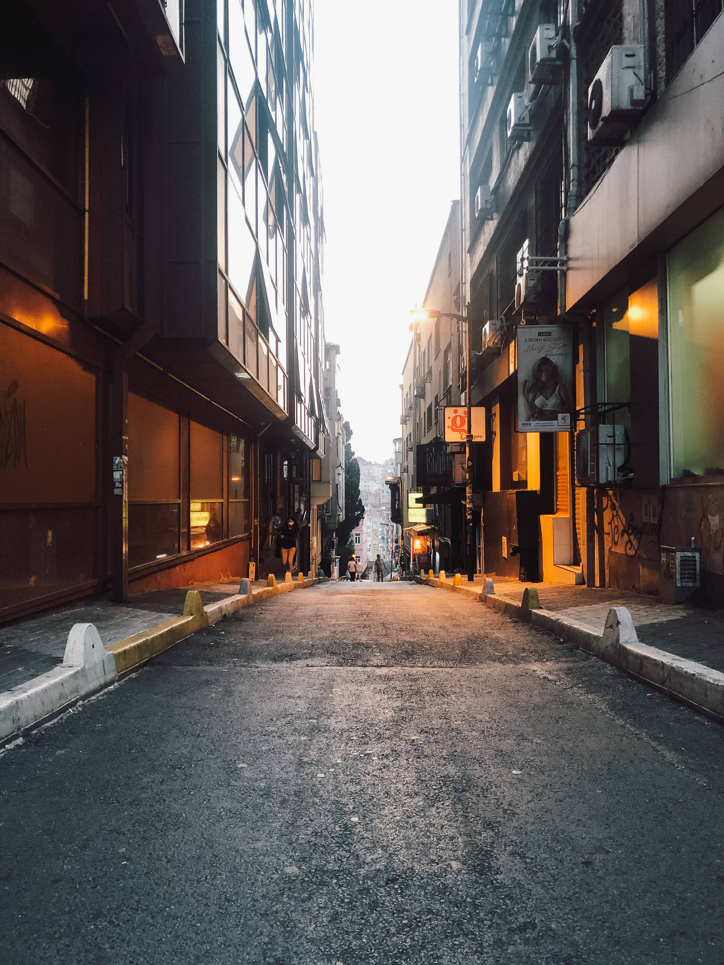 黃昏時分，狹窄的城市小巷，燈光閃爍，遠處有行人。