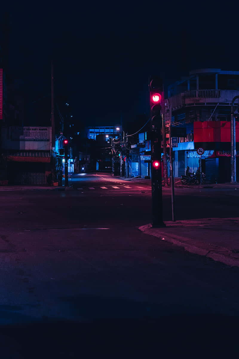 夜晚霓虹燈照亮的街角，帶有發光的紅色交通燈。