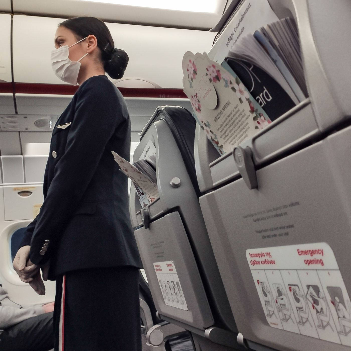 穿著制服和口罩的空中服務員站在飛機機艙內座位附近。