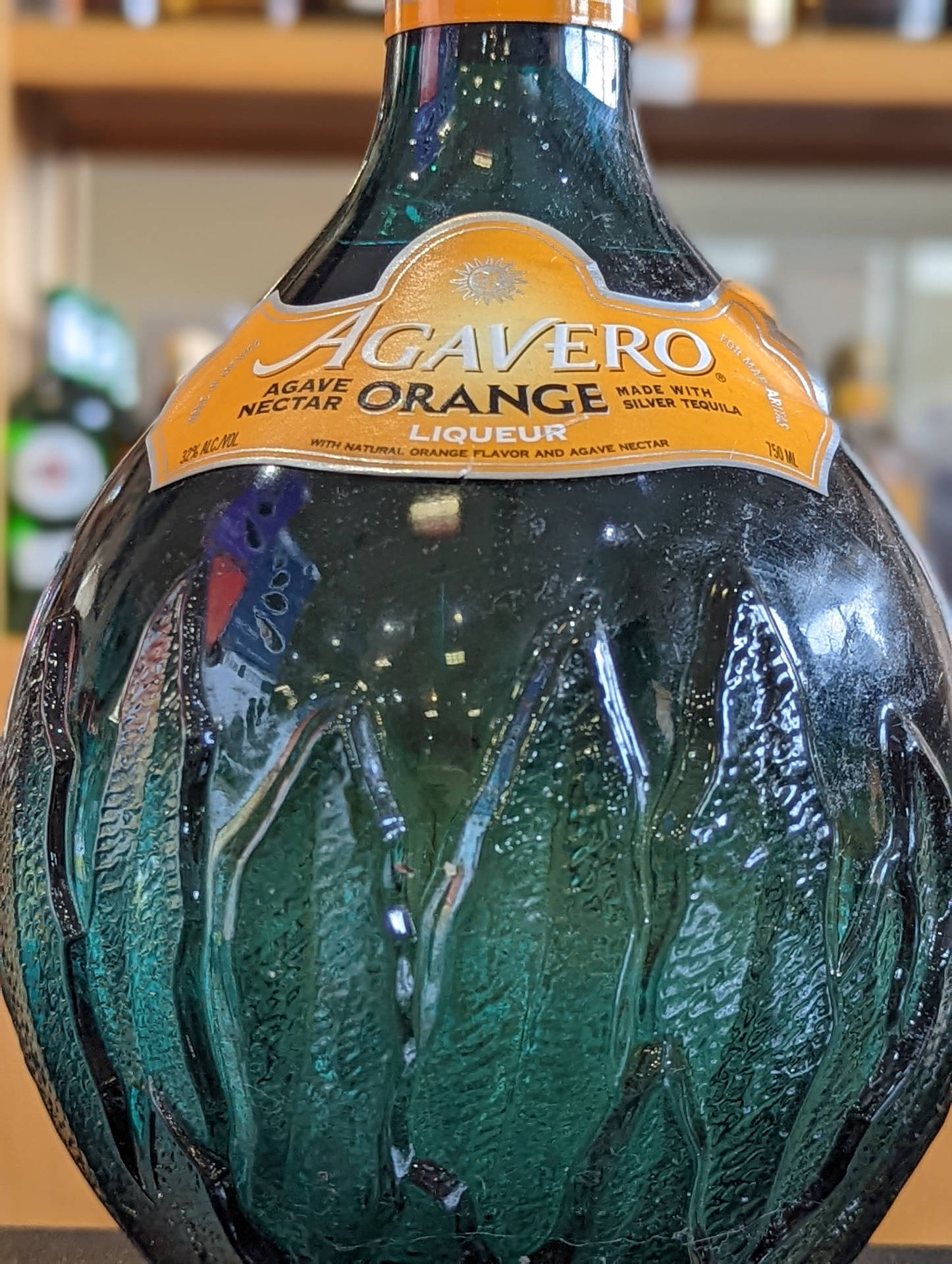 Agavero Orange 利口酒嘅青綠色玻璃樽，有紋理設計同橙色標籤。