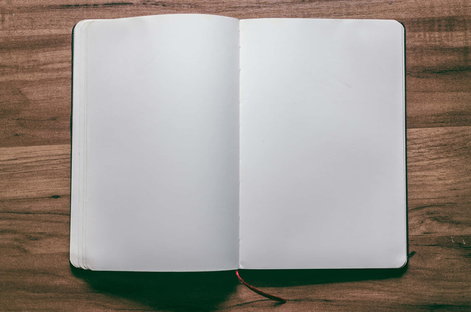木桌上打開的空白筆記本，準備書寫