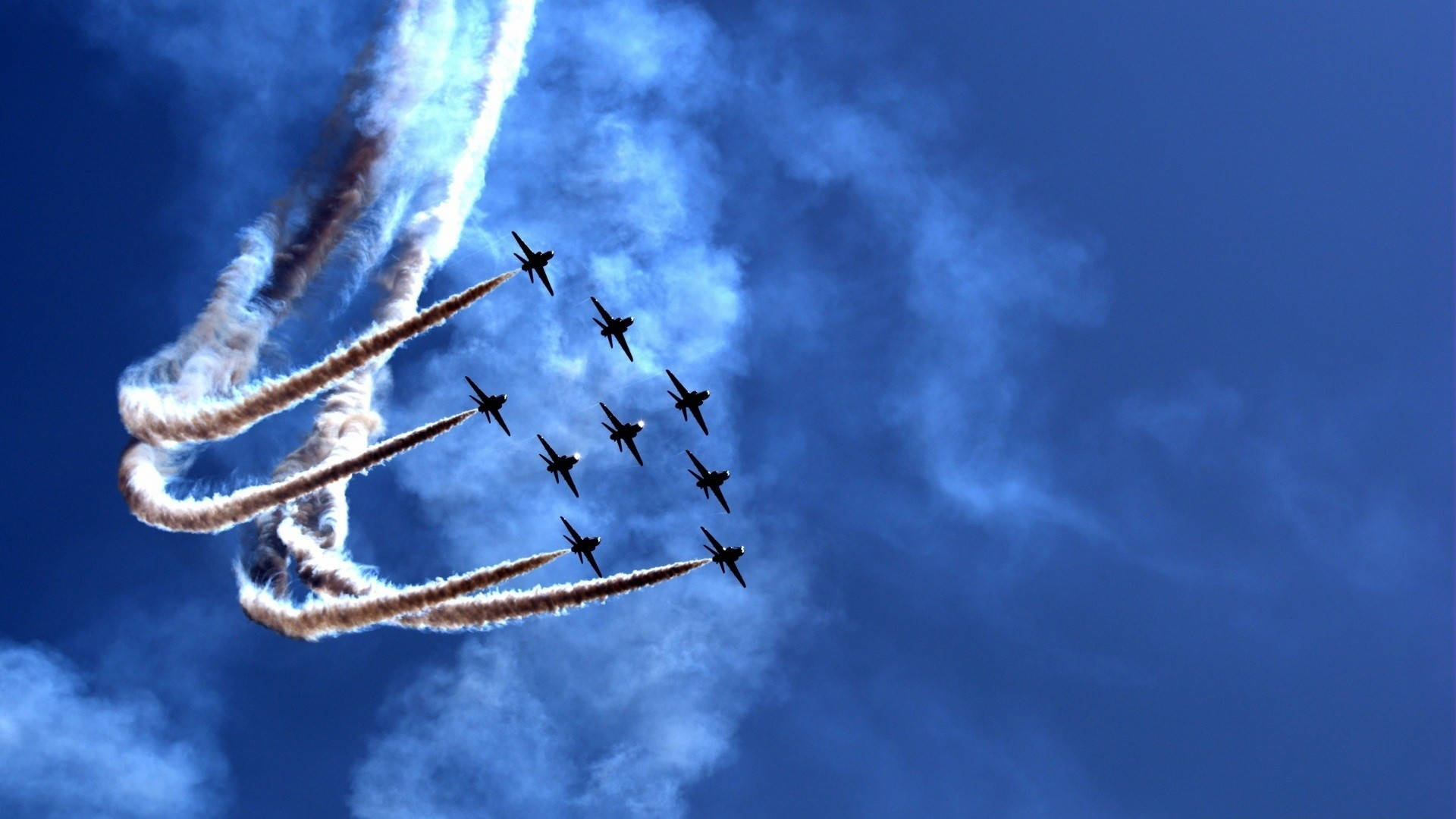 空軍戰機留煙 壁紙 — 九架戰鬥機在深藍色的天空中緊密編隊飛行，留下濃厚的白色煙霧痕跡。