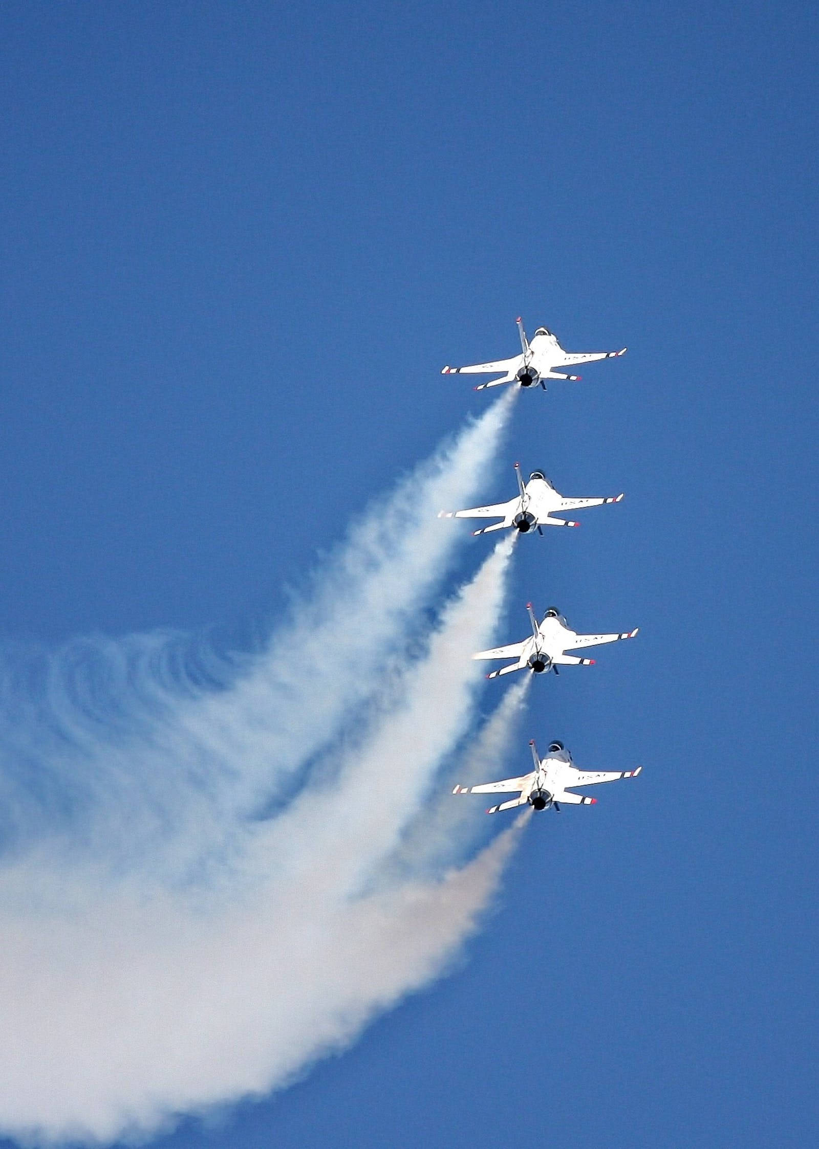 空軍戰鬥機表演 壁紙 — 四架白色戰鬥機在晴朗的藍天下以緊密編隊飛行，留下濃厚的白色煙跡。