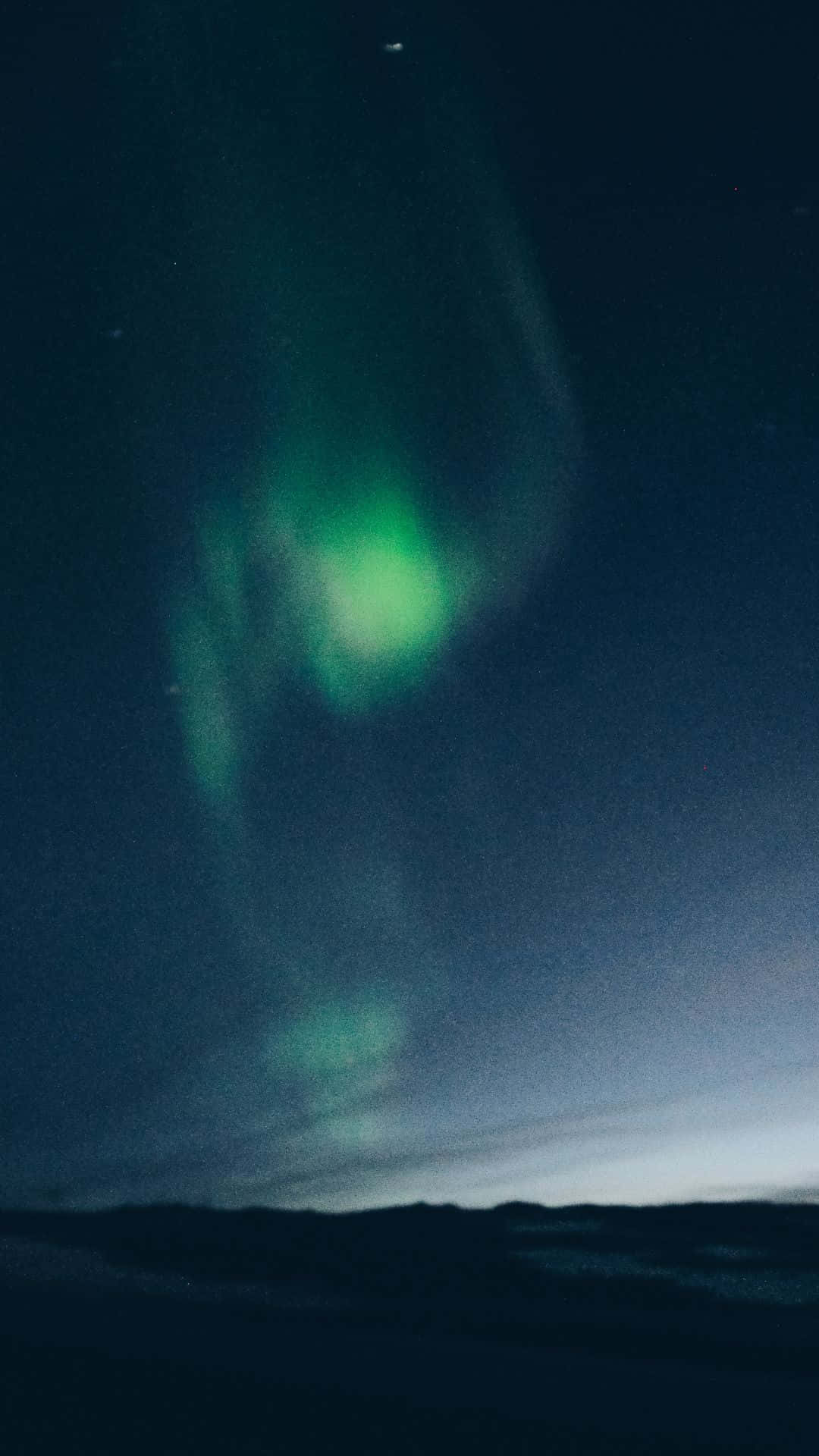 綠色北極光在繁星點點的夜空中閃爍，籠罩在黑暗的景觀之上。