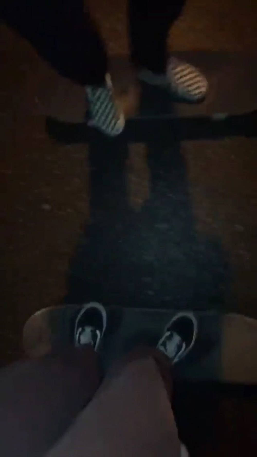 穿 Vans 鞋的滑手夜間滑板，滑板風格 壁紙 — 第一人稱視角，夜晚兩個人站在滑板上，在鋪砌的地面上投下長長的影子。