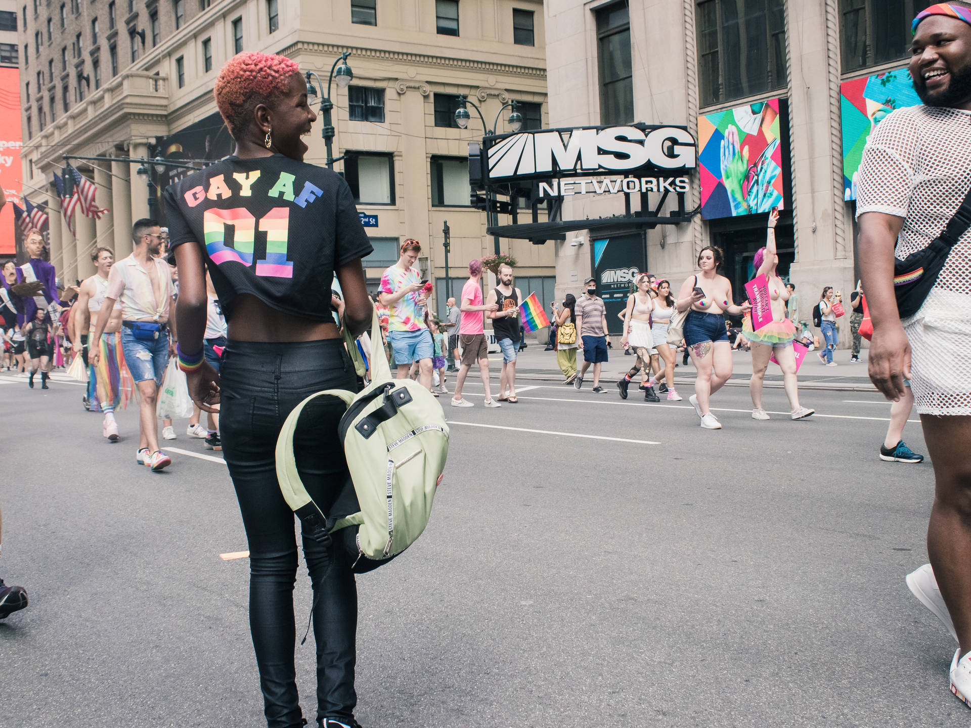 人群在城市街道上以彩虹旗和色彩繽紛的服裝慶祝Pride。