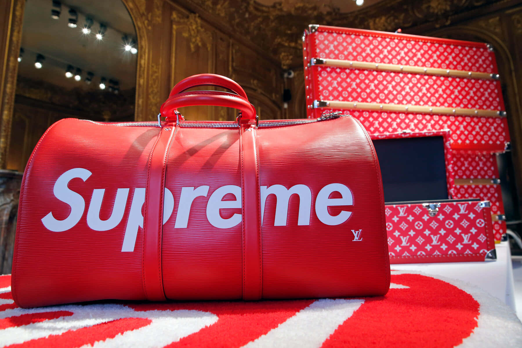 紅色 Supreme x Louis Vuitton 行李袋和行李箱在豪華的金色環境中展示。