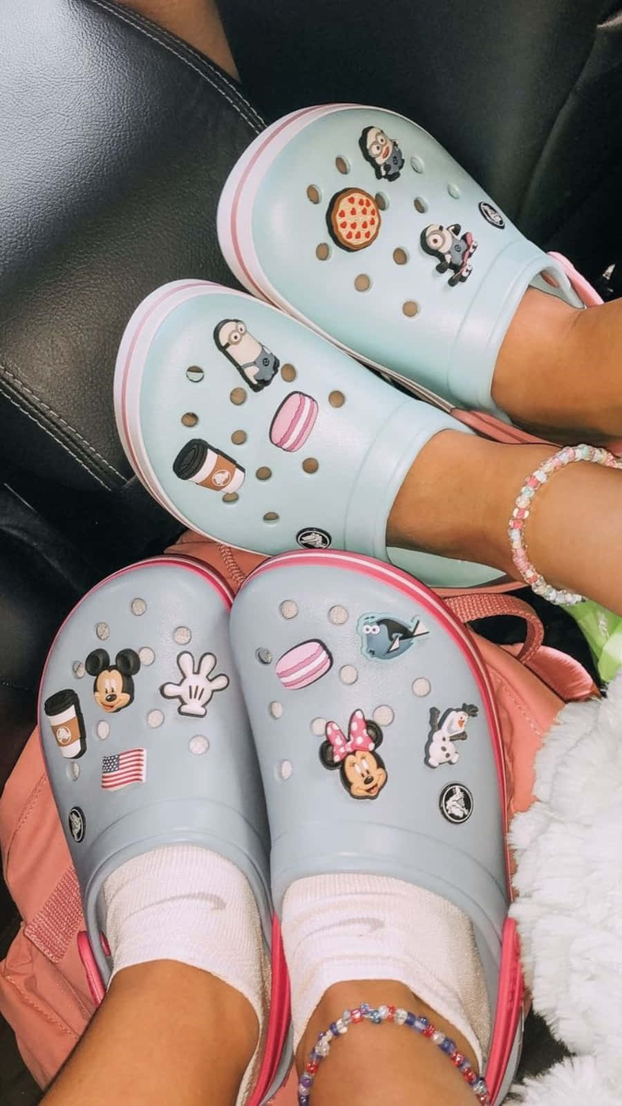 兩個人穿著裝飾過的Crocs鞋，帶有迪士尼和迷你兵團吊飾，坐在梳化上。