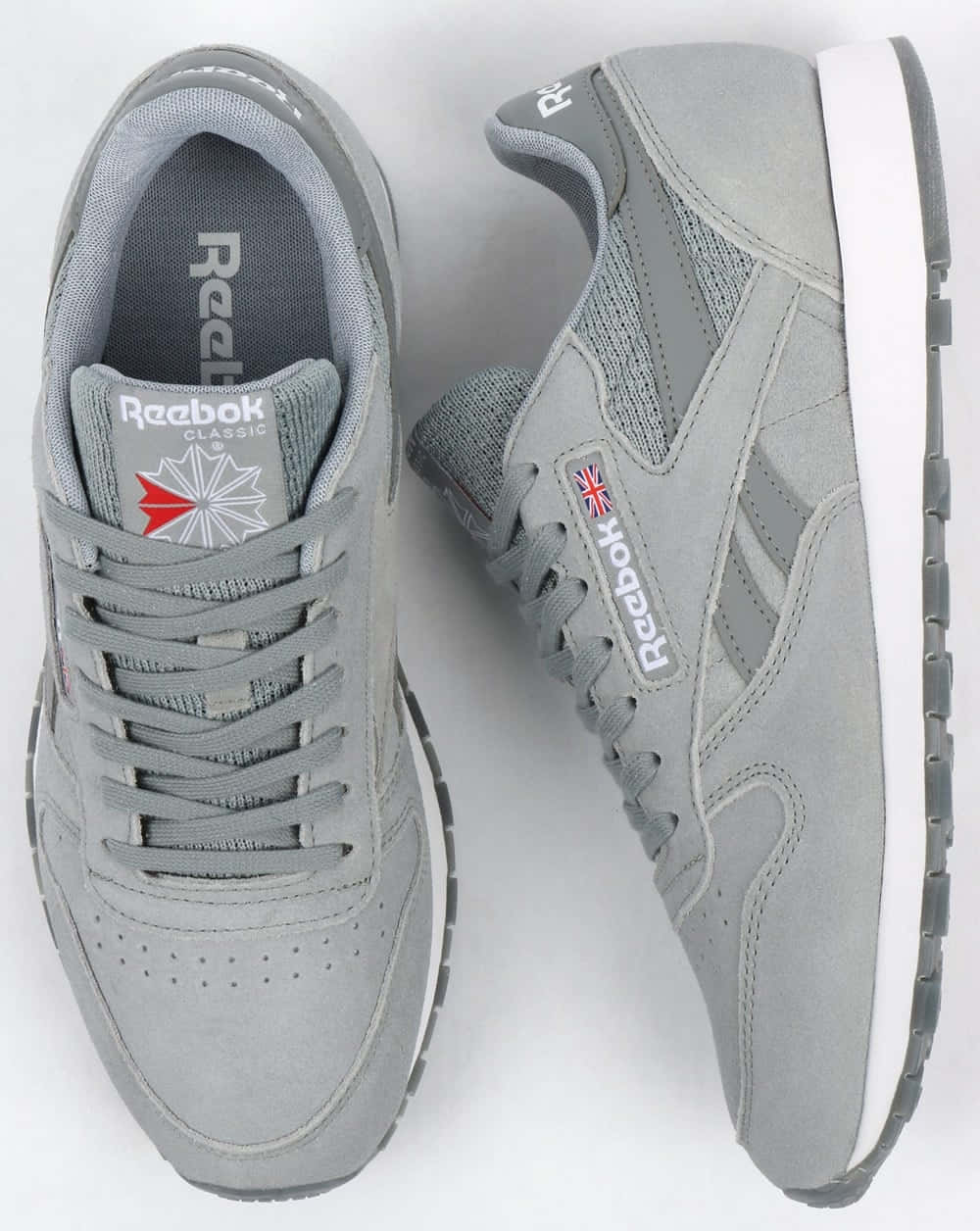 穿上Reebok，釋放內在運動員！ 壁紙 — 一對灰色 Reebok Classic 運動鞋，白色鞋底，帶有英國國旗品牌標誌，從頂部和側面展示。