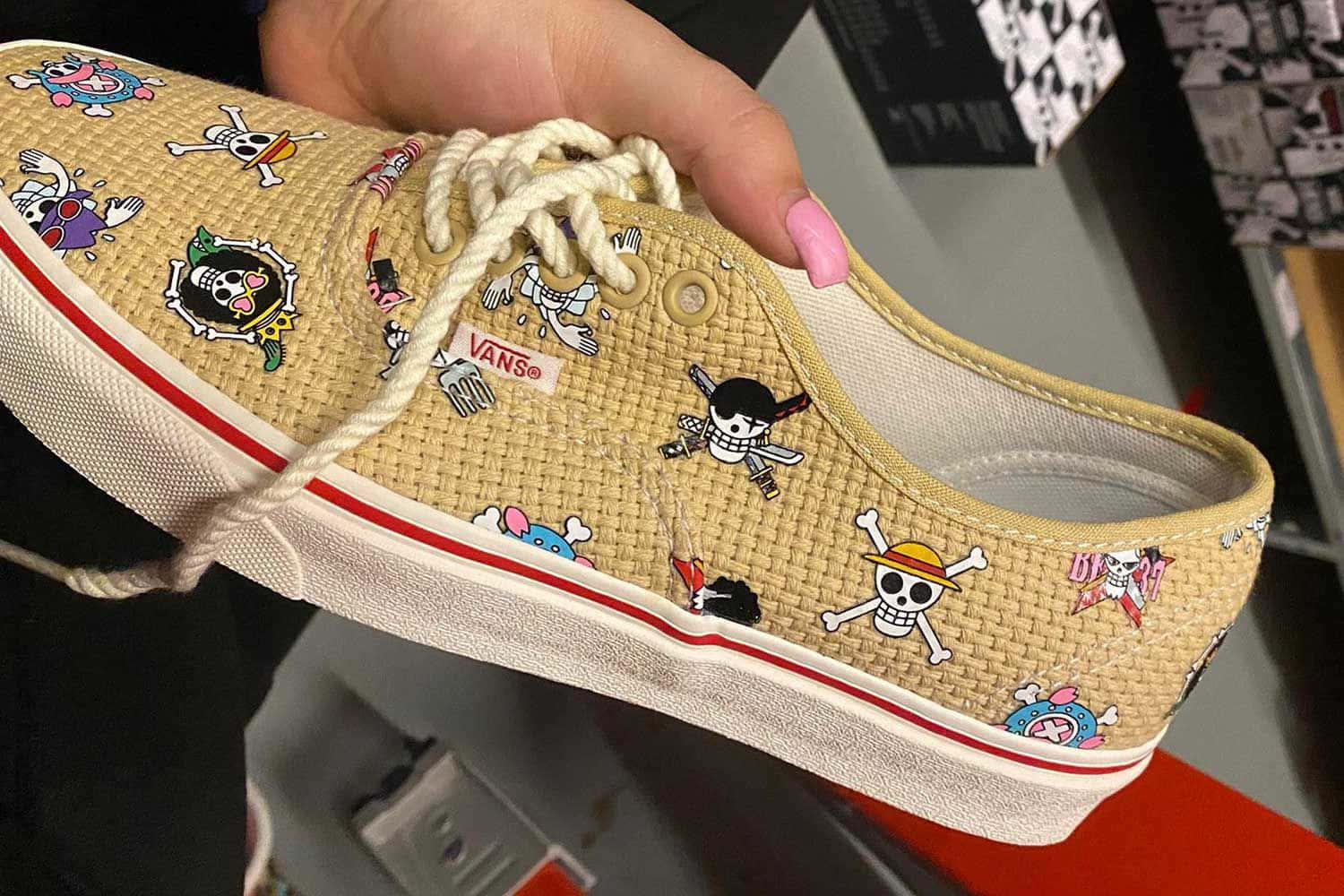 手拿米色Vans運動鞋，帶有One Piece動漫角色貼片。