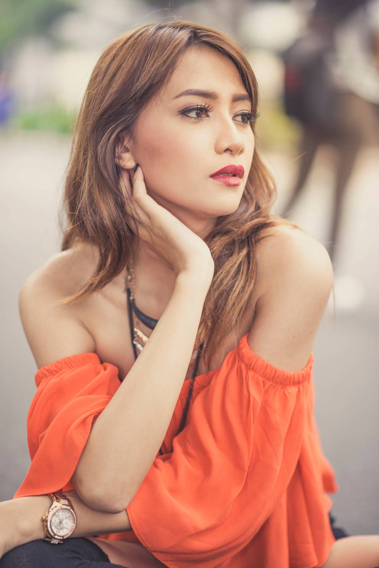 一位身穿橙色上衣的女性在日落時分在戶外若有所思地擺姿勢。