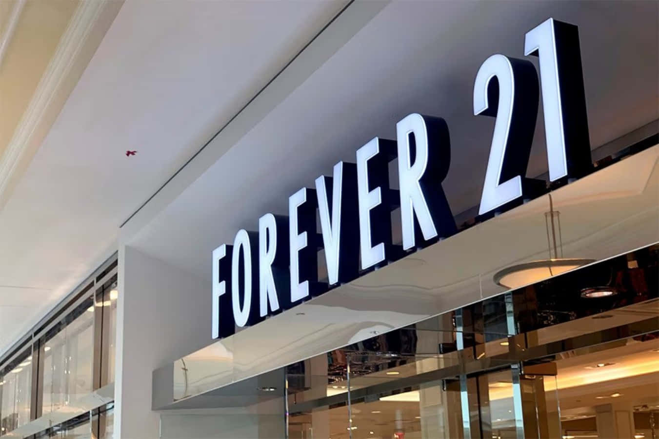 穿出時尚，展現最佳狀態 — Forever 21 壁紙 — 商場內玻璃店面上方安裝的發光Forever 21商店招牌特寫。