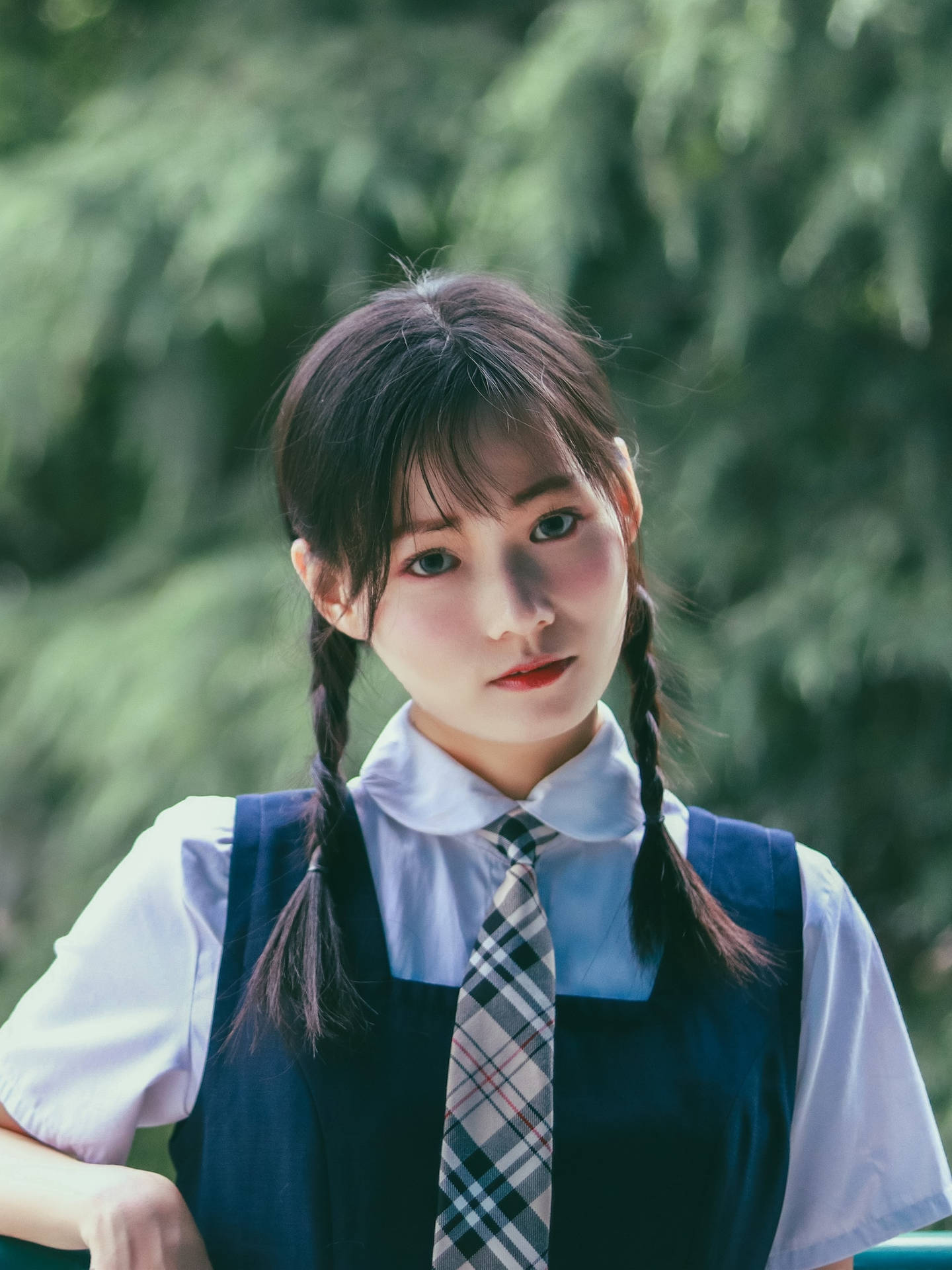 一位辮子女孩穿著校服和格子領帶在戶外。