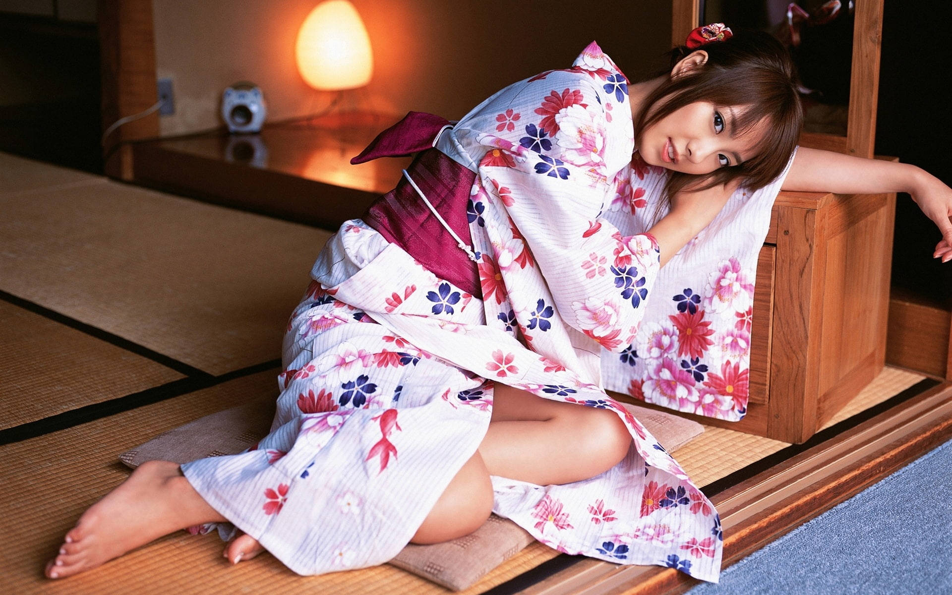 穿著花卉圖案浴衣的年輕女性在傳統日式房間的榻榻米上休息。