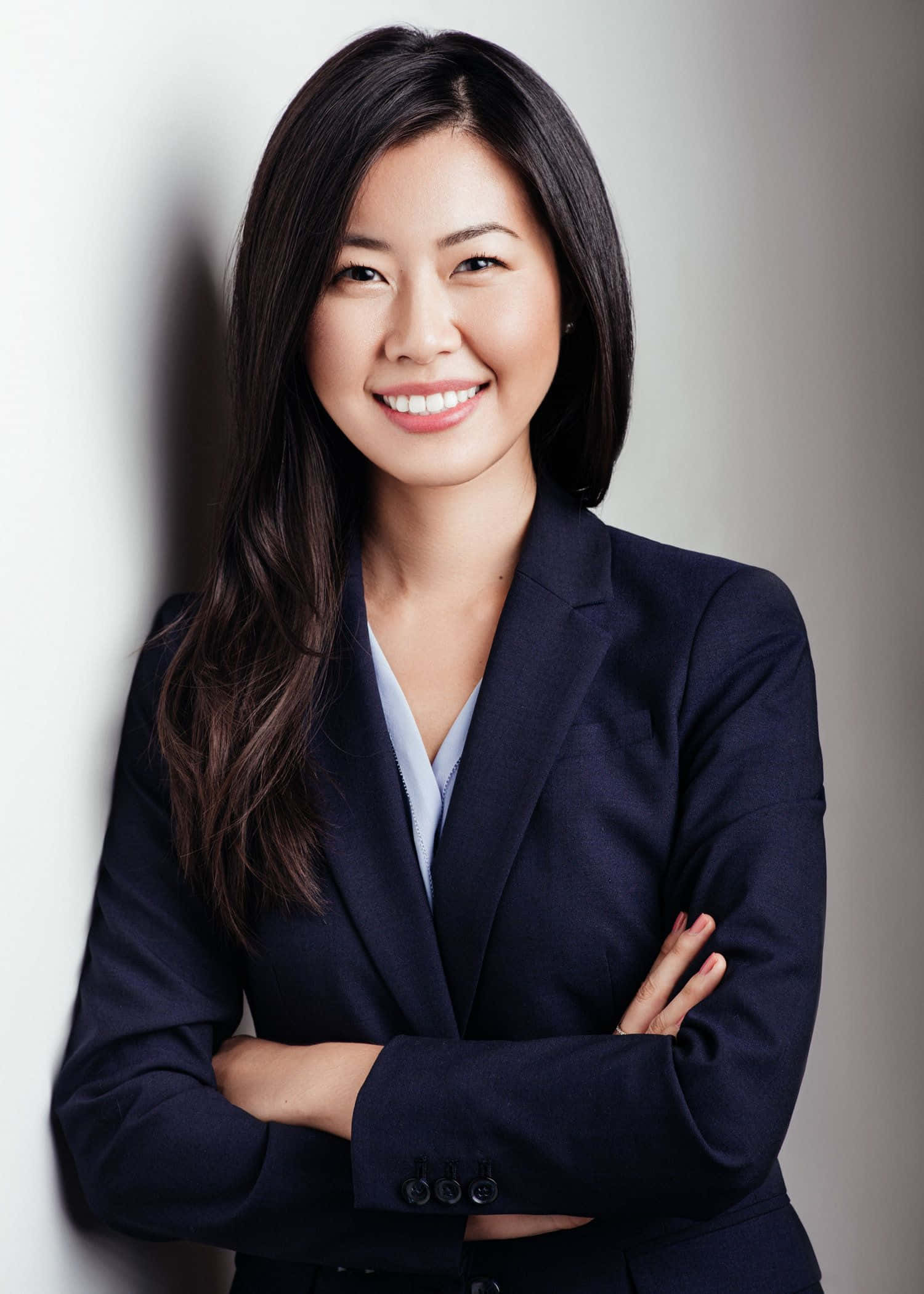 穿正裝的自信專業人士個人頭像 壁紙 — 一位自信的亞洲女商人交叉雙臂，對著白色牆壁微笑，專業工作室肖像。