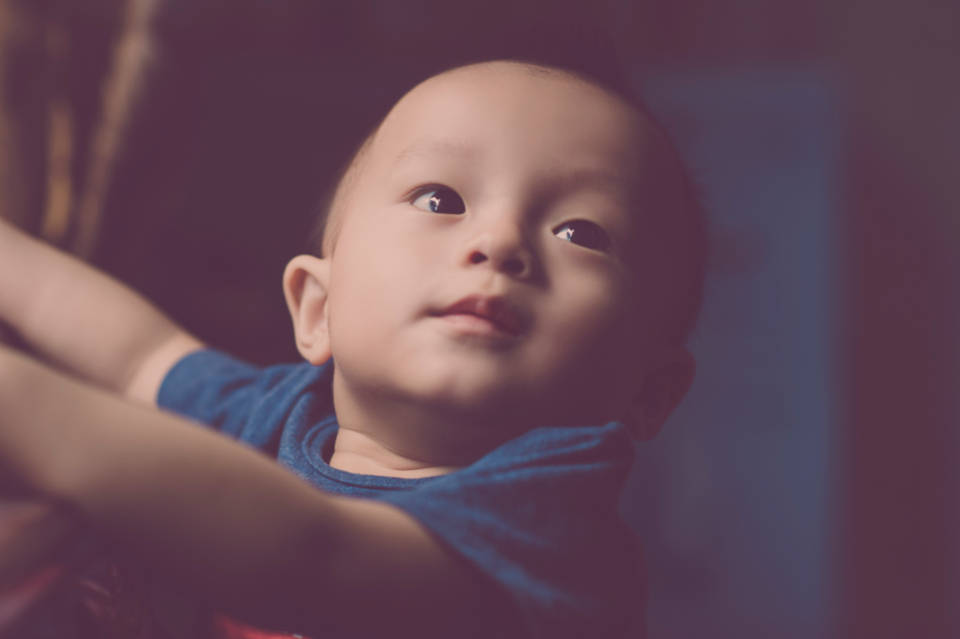 穿深藍色襯衫男嬰 壁紙 — 一個穿著藍色襯衫的嬰兒特寫，睜著好奇的大眼睛向上看，背景柔和模糊。