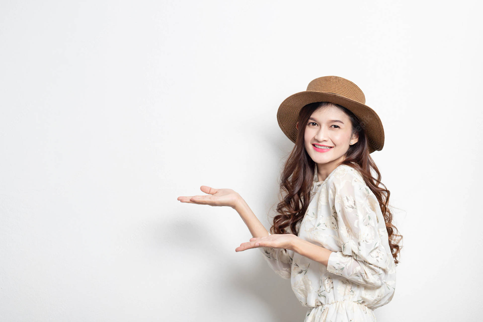 戴草帽女性在白色背景前張開雙手展示