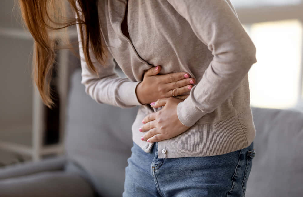 女性因疼痛捂著腹部（室內）