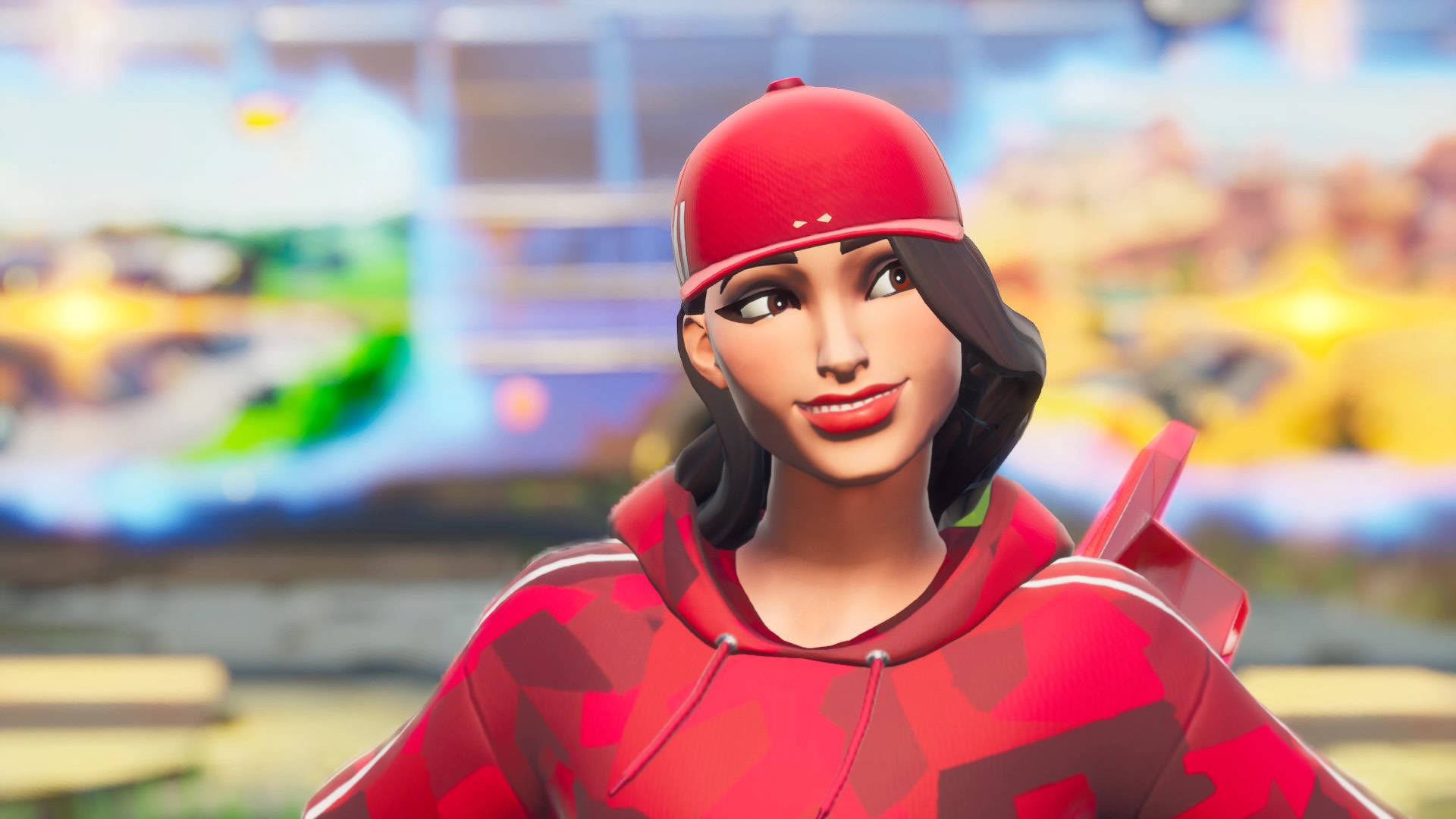 穿紅色服裝的快樂魯比《Fortnite》 壁紙 — 一個戴紅色帽同著連帽衫嘅Fortnite角色喺色彩繽紛模糊嘅遊戲背景中自信咁微笑。