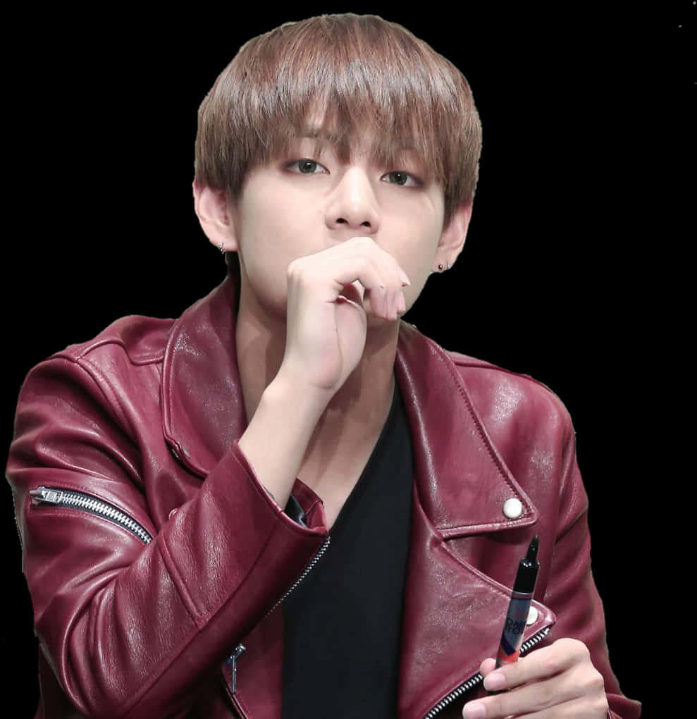 穿紅色皮夾克沉思的男子 壁紙 — 一位棕色頭髮的年輕男子穿著紅色皮夾克，手持筆，下巴擱在手上，背景為黑色。