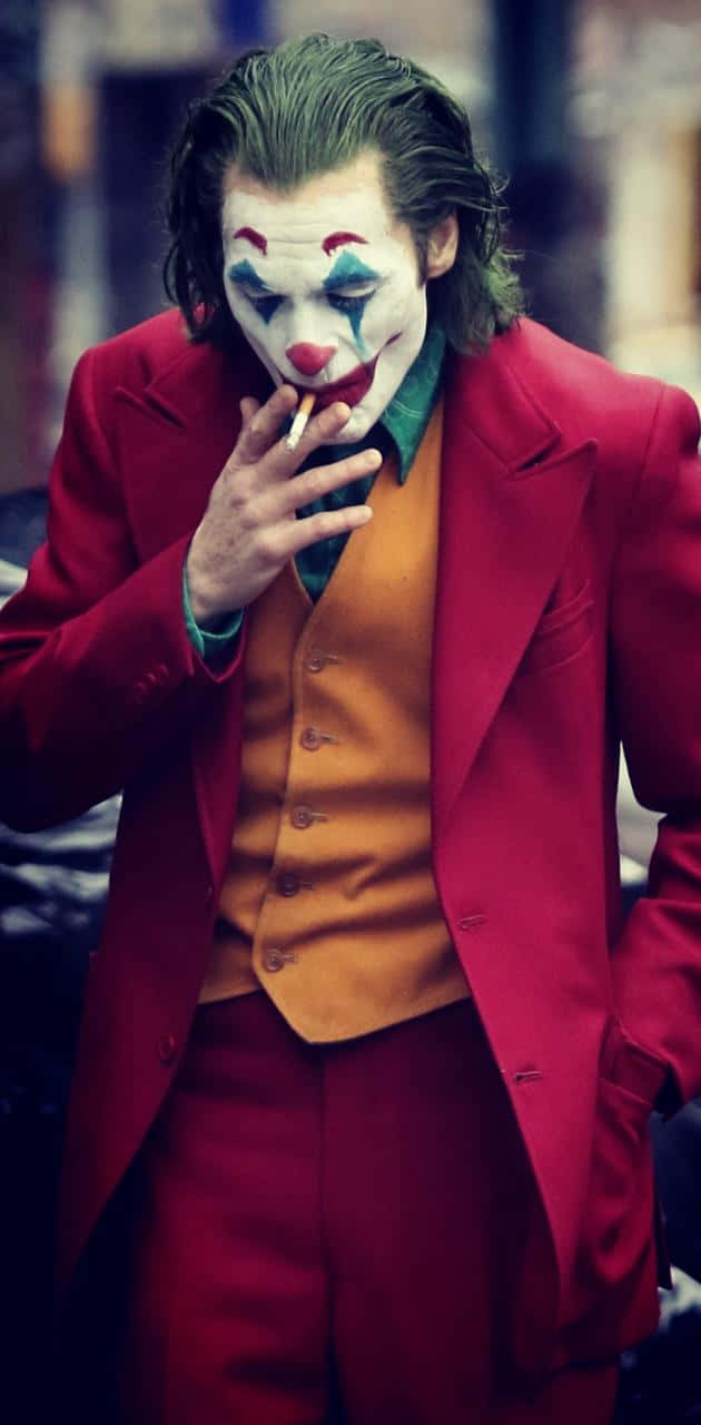 一名打扮成小丑的男子在城市環境中抽煙。