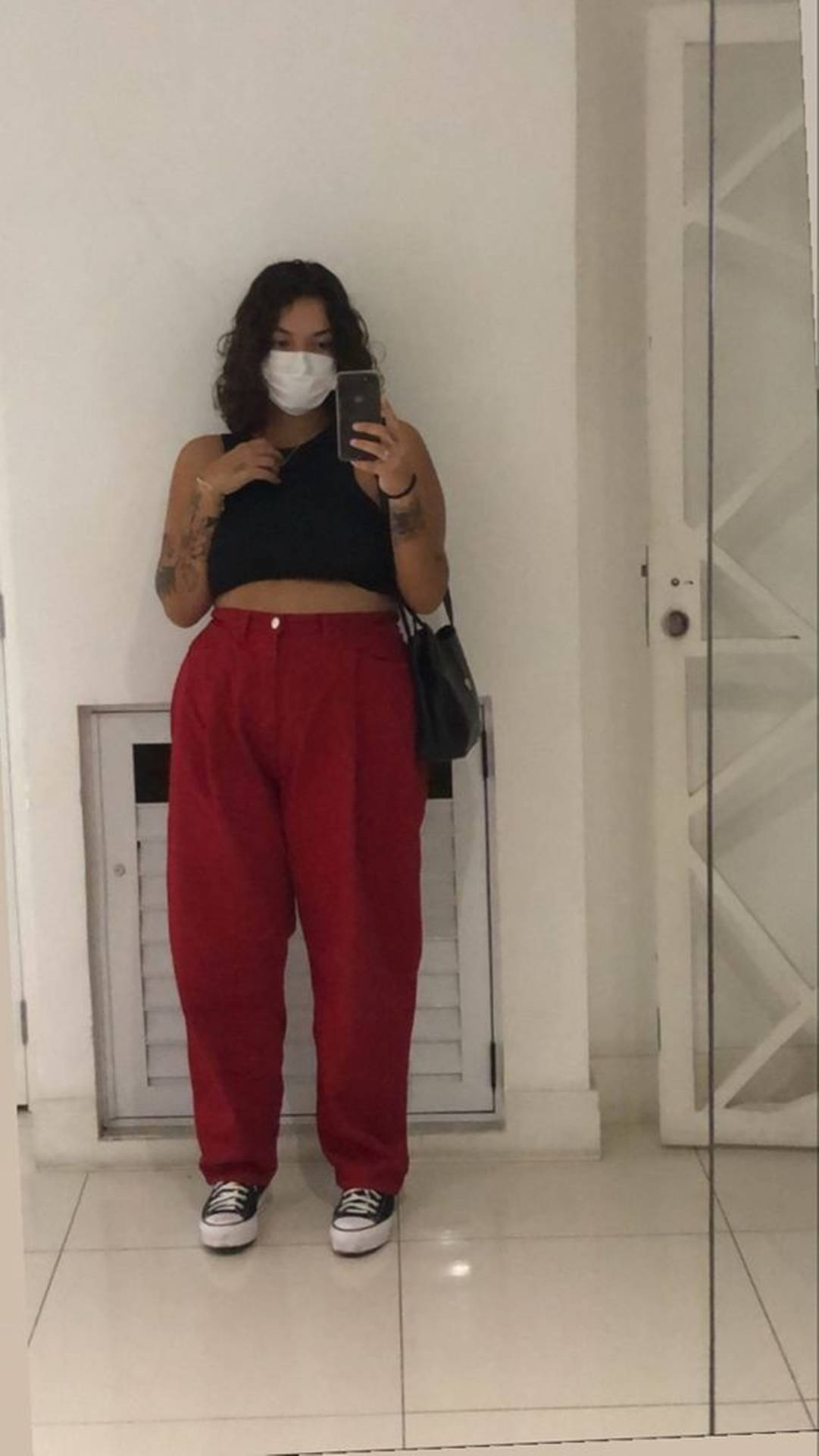 穿著紅色褲子和口罩的人在室內對著鏡子自拍