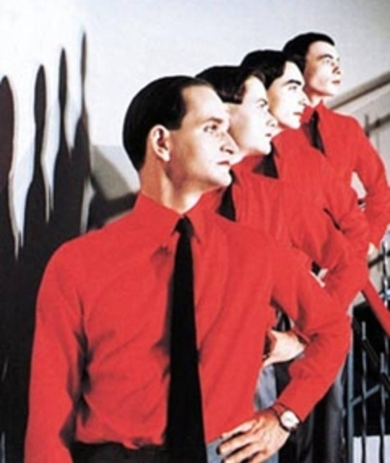 穿紅襯衫的 Kraftwerk — 階梯上的音樂力量 壁紙 — 四個穿著相同紅色襯衫和黑色領帶的男人排成一排，側視著一面帶有黑色抽象形狀的純白牆壁。