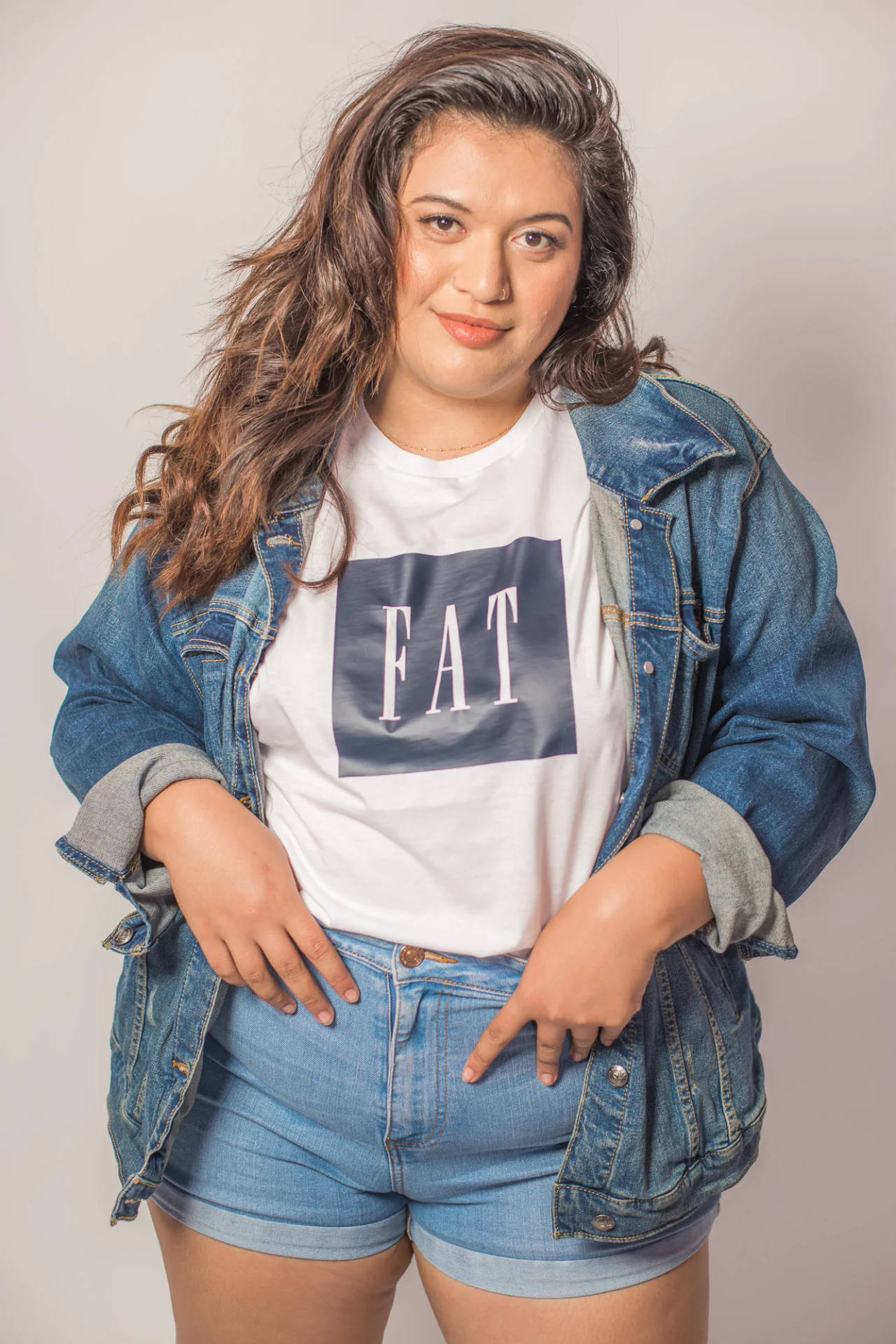 穿著牛仔外套和短褲的女性，T恤上有「FAT」文字。