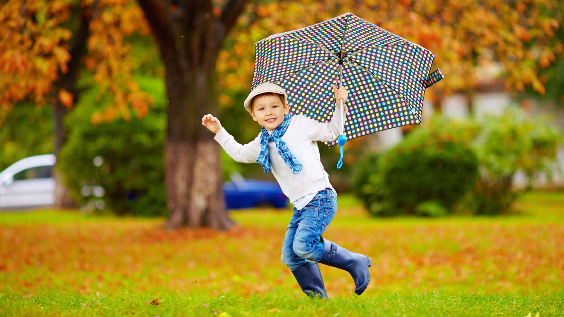 孩子在秋日公園中拿著彩色雨傘在雨中奔跑