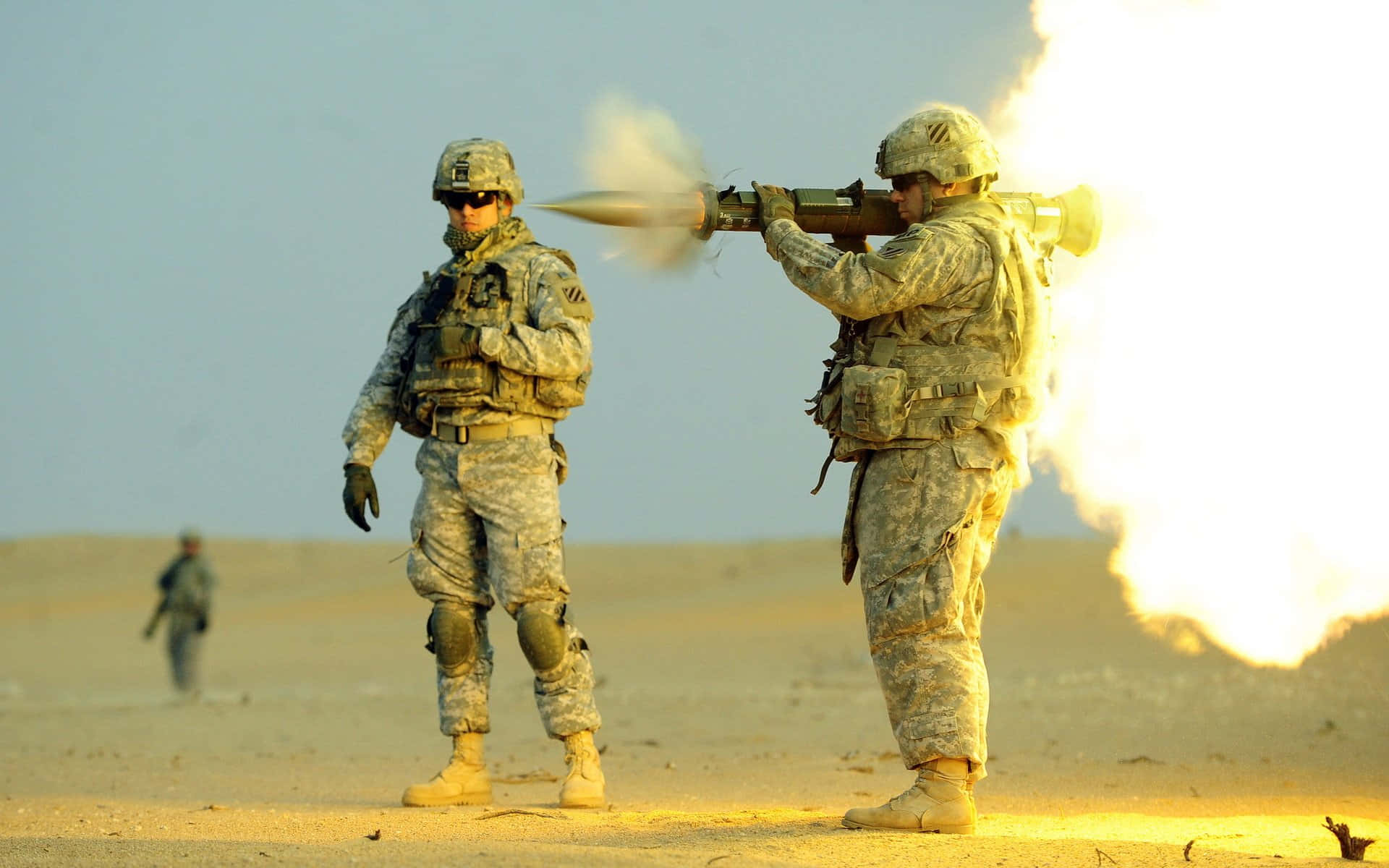 Army 桌布 壁紙 — 穿著沙漠迷彩服的士兵在朦朧的天空下發射火箭筒，伴隨著明亮的槍口閃光。