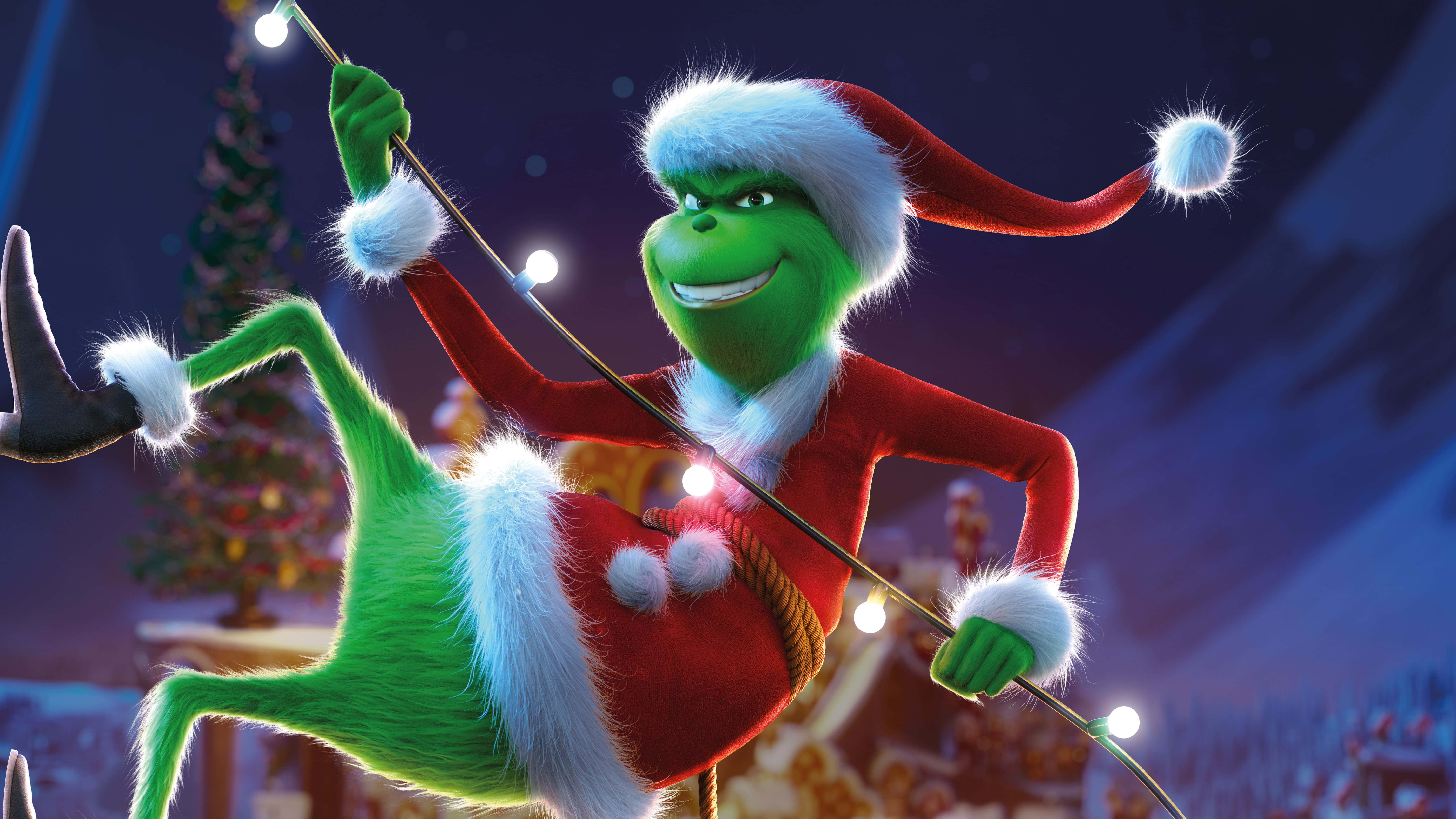 Cute Grinch 桌布 壁紙 — 穿著紅色聖誕老人服的鬼靈精，在雪夜背景下快樂地在一串發光的燈上搖擺。