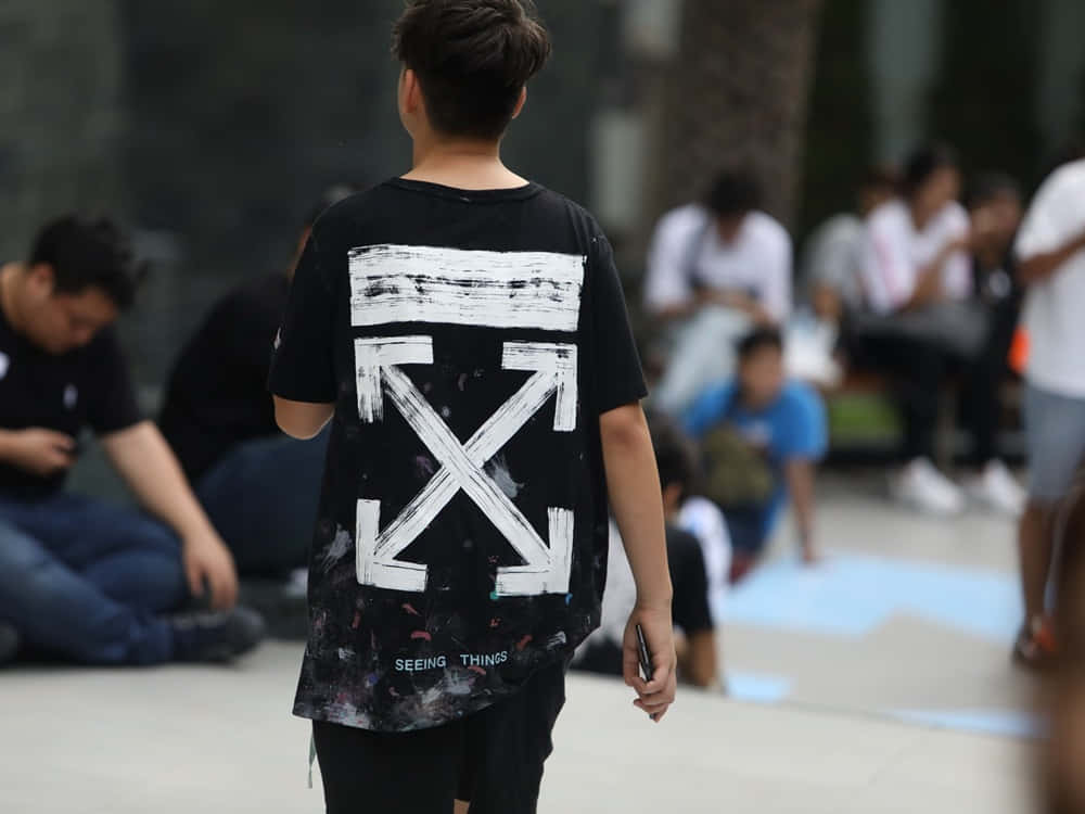 年輕人在城市環境中穿著黑色Off White T恤走開。
