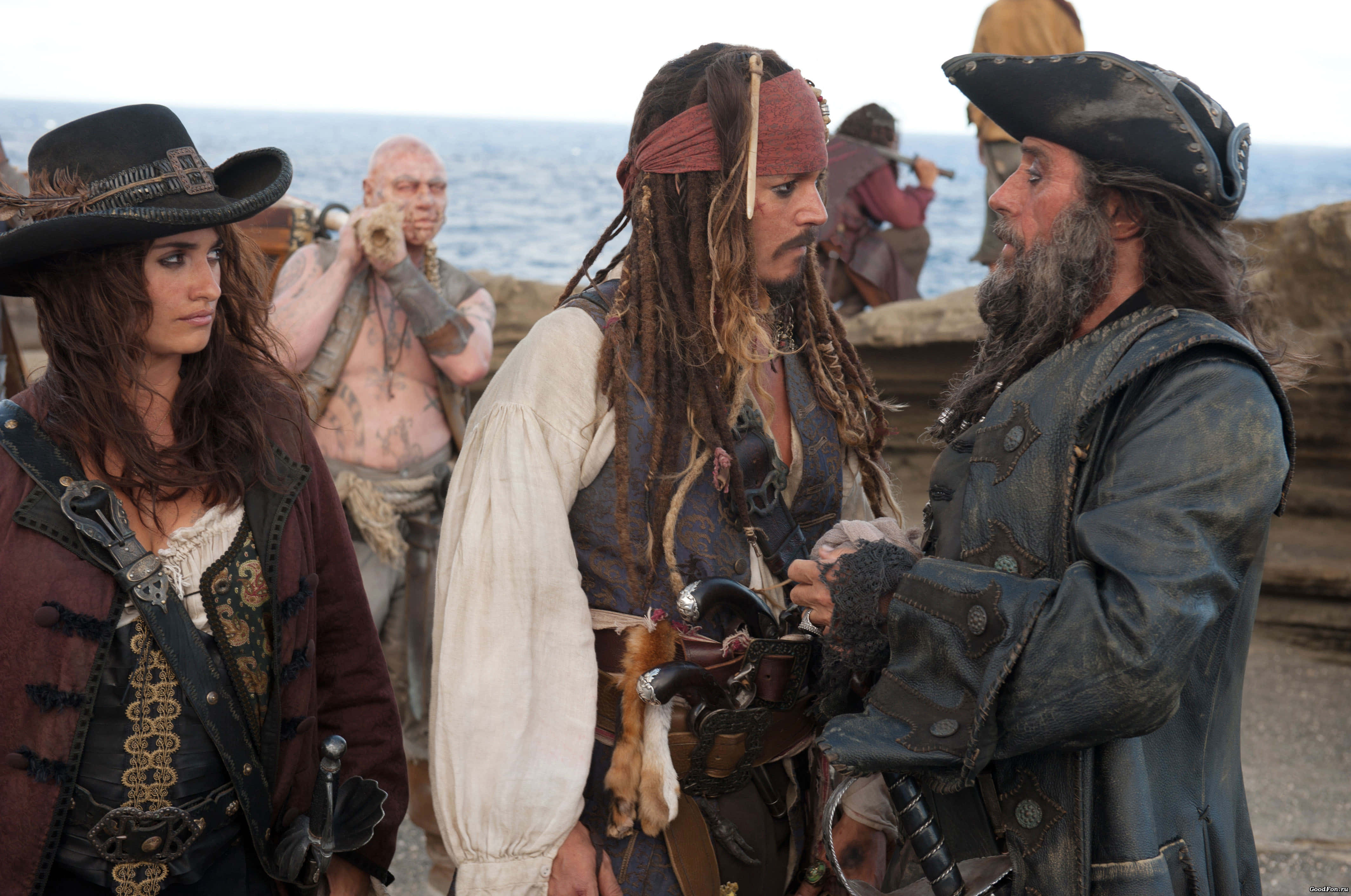 Pirates Of The Caribbean 桌布 壁紙 — 穿著風化服裝的海盜在岩石海岸上交談，身後是海洋。