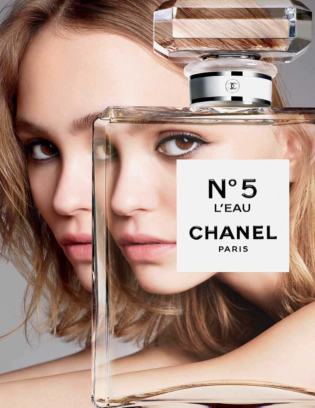 穿著香奈兒，感受時尚與優雅 壁紙 — 女性的臉孔與Chanel No 5 L'eau香水瓶融合，營造出超現實而優雅的視覺效果。