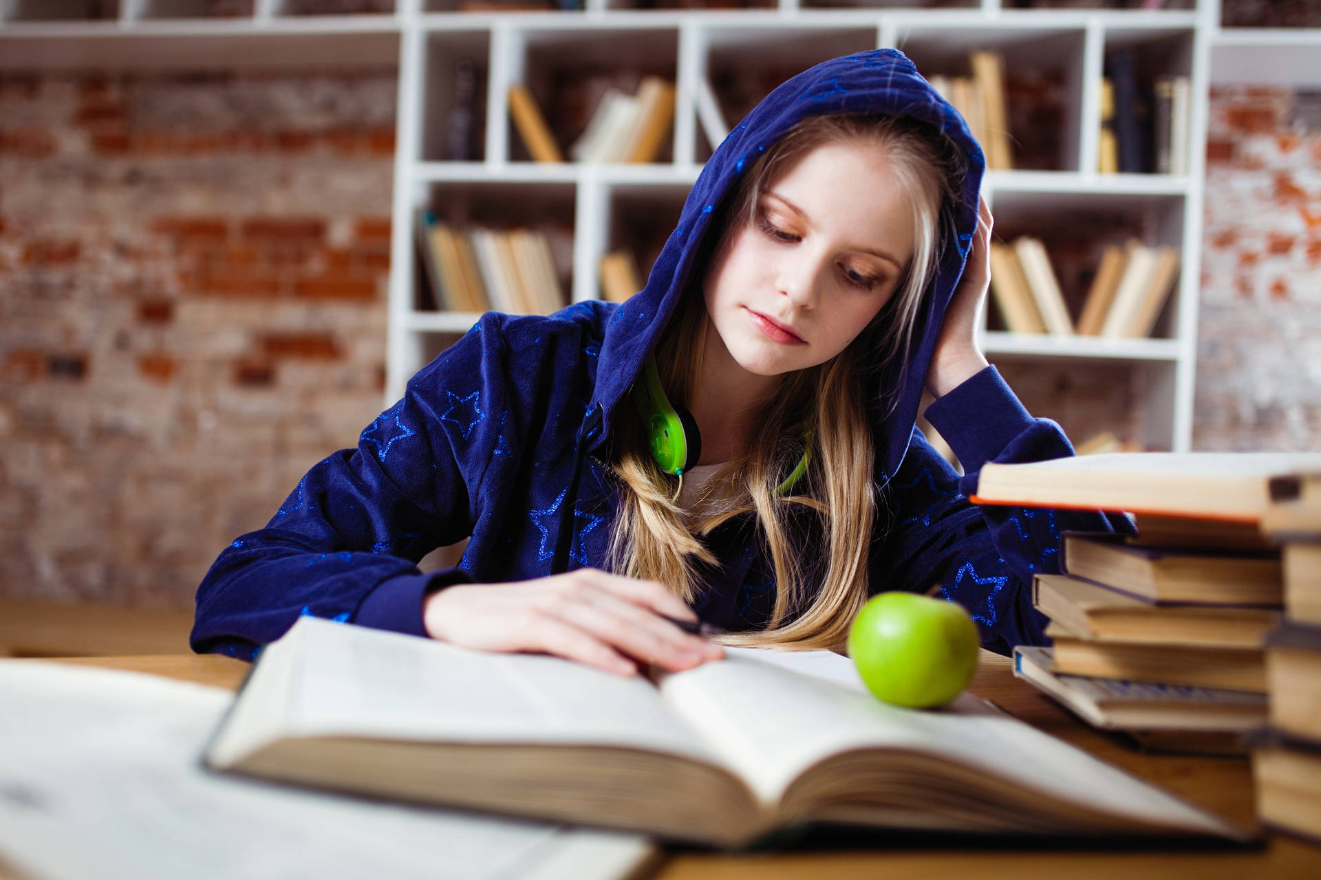 年輕女性在木桌上用書籍和蘋果學習
