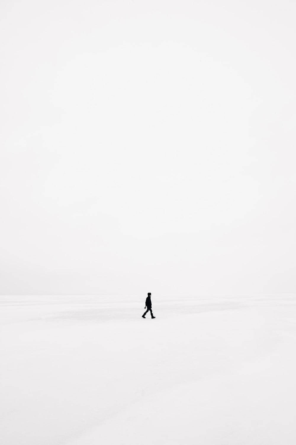 一個人在蒼白的天空下獨自走過雪地。