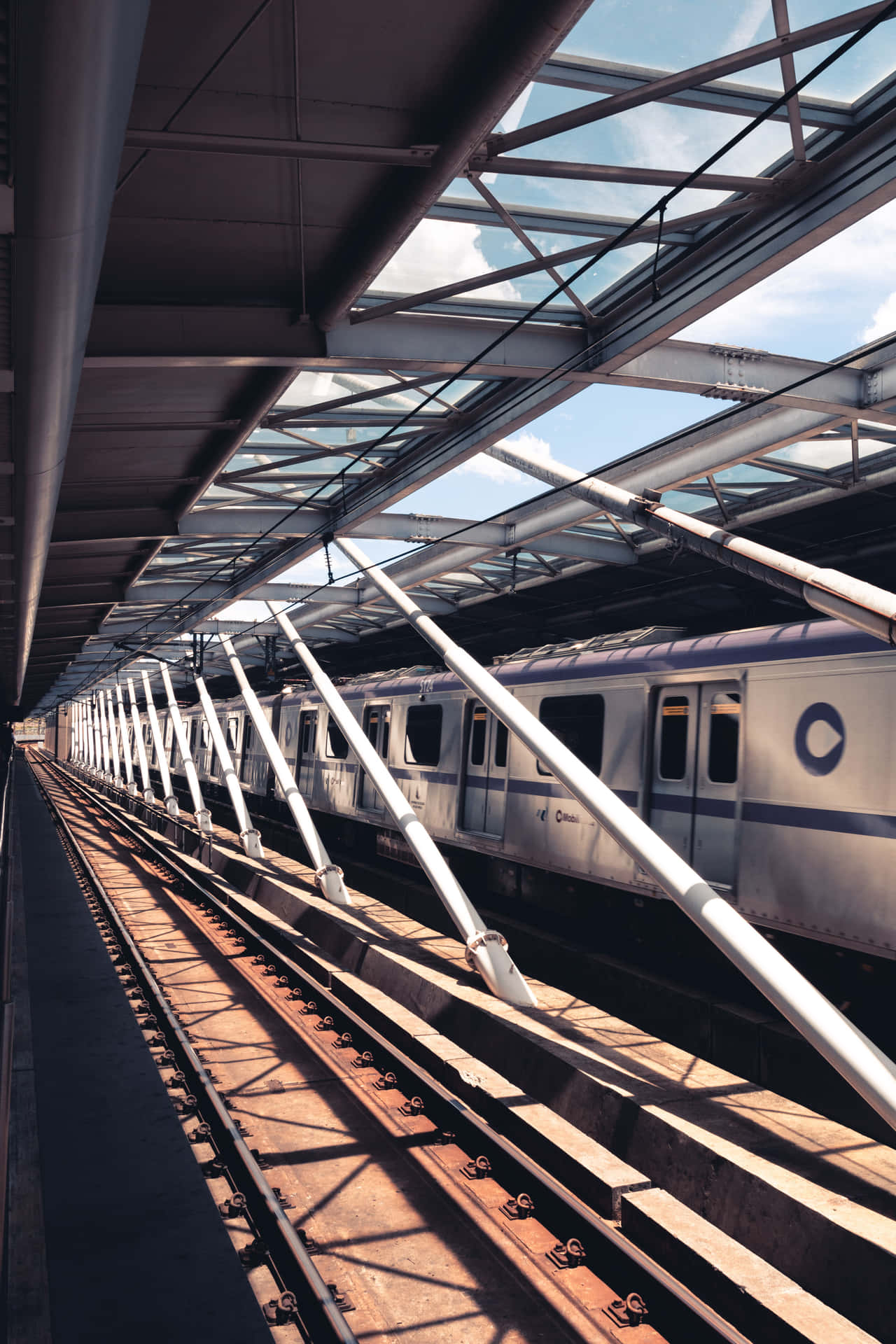 高架車站玻璃屋頂下的銀色列車，陽光投下陰影