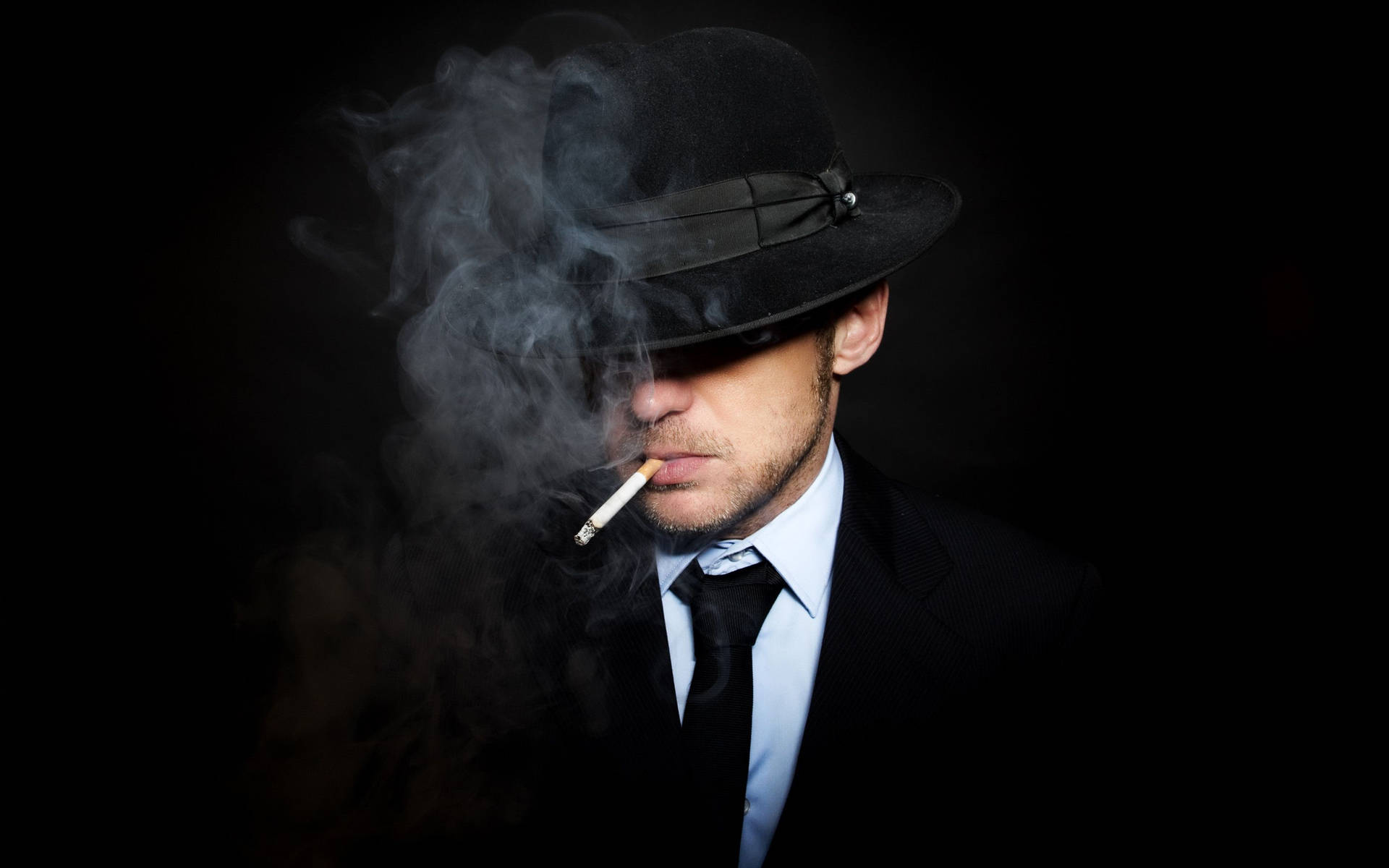 戴黑色軟呢帽的男人抽煙，煙霧在臉龐周圍繚繞。