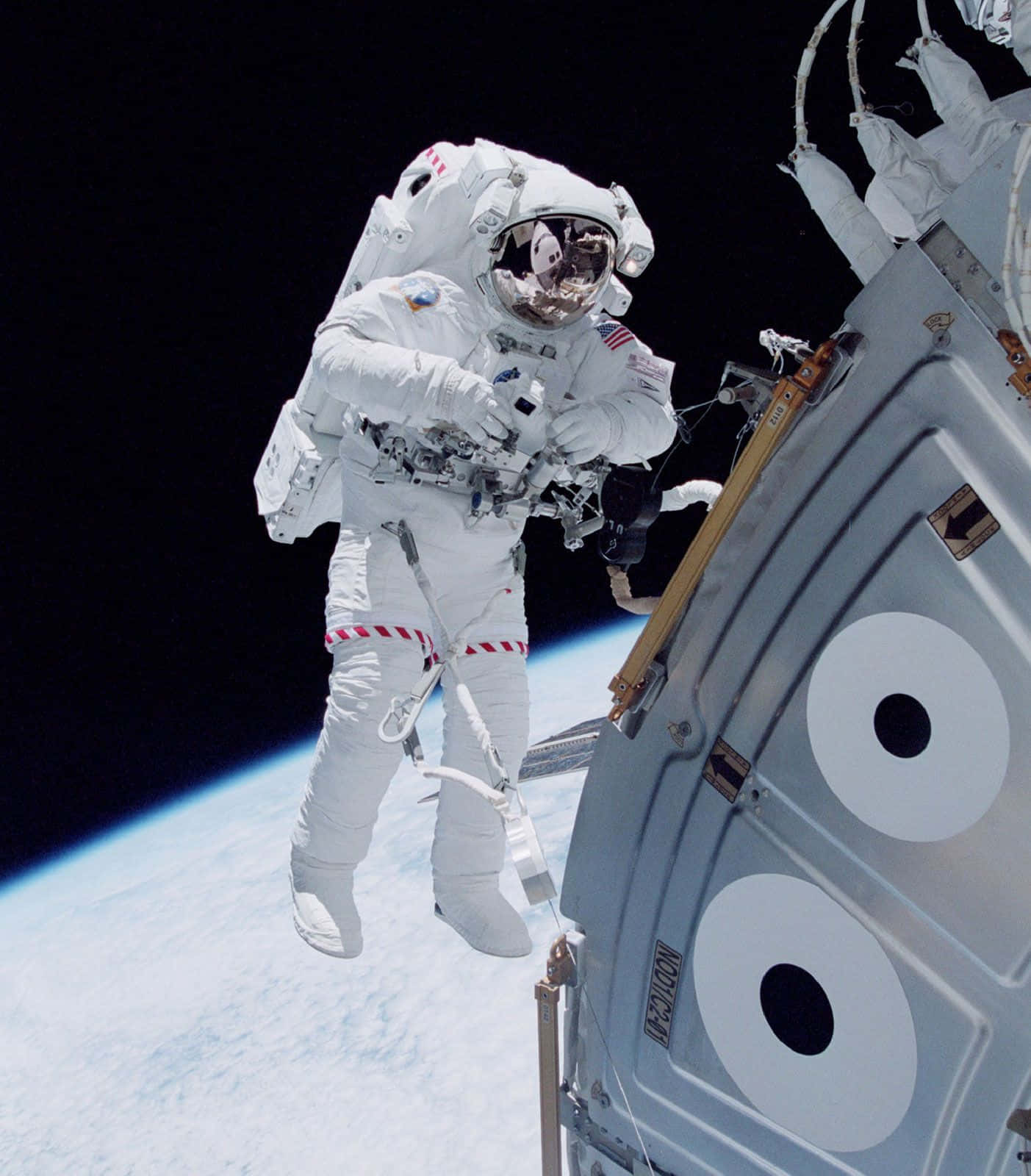 穿越宇宙之旅 壁紙 — 一名穿著白色太空衣的太空人在太空船外進行太空漫步，下方可見地球彎曲的地平線。