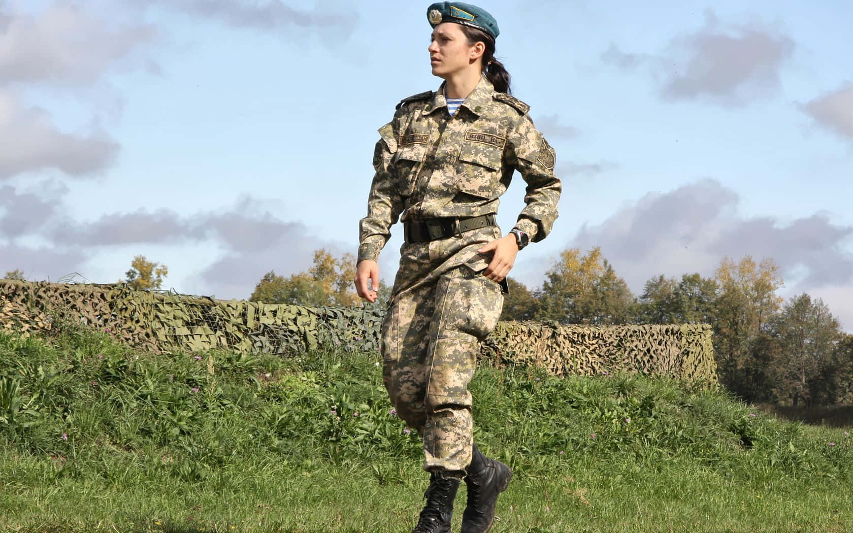 身穿迷彩制服的女兵在戶外草地上行走。