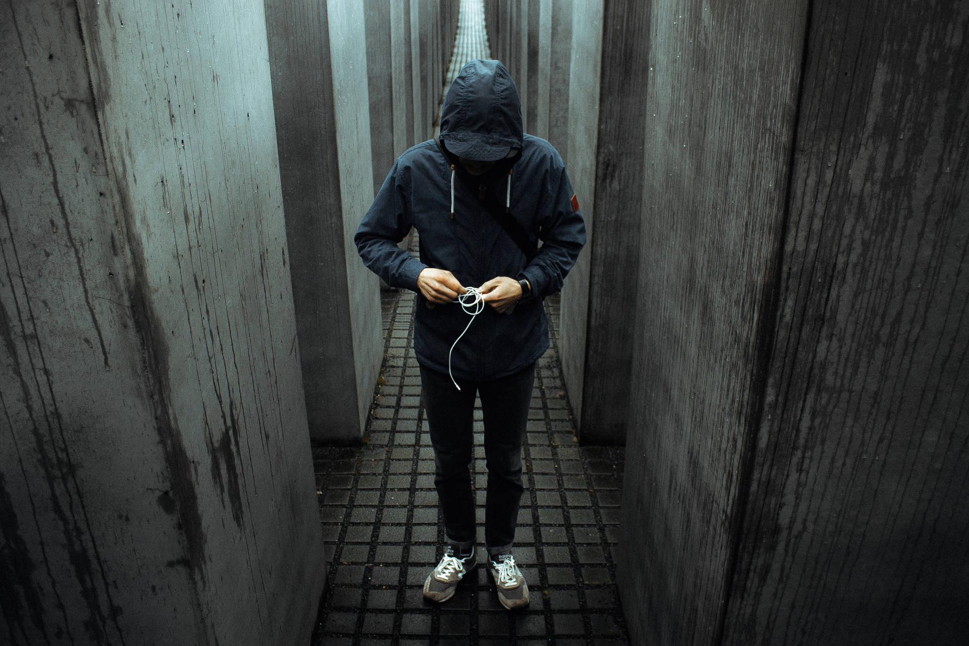 穿著深色連帽衫的人站在混凝土走廊裡拿著耳塞